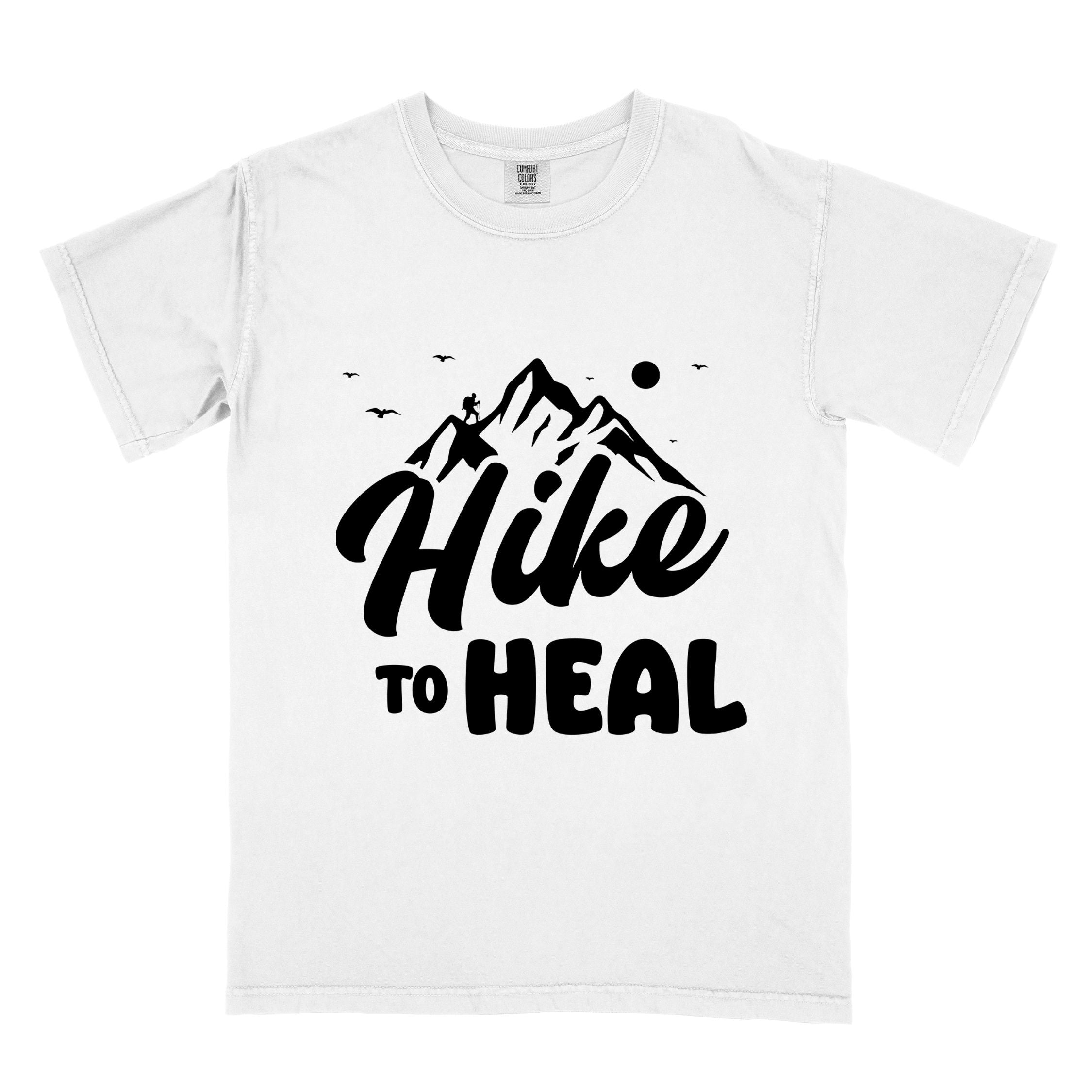 White "Hike to Heal" colored statement tee with bold typography, mountain, sunrise, perfect for adventure driven individuals.