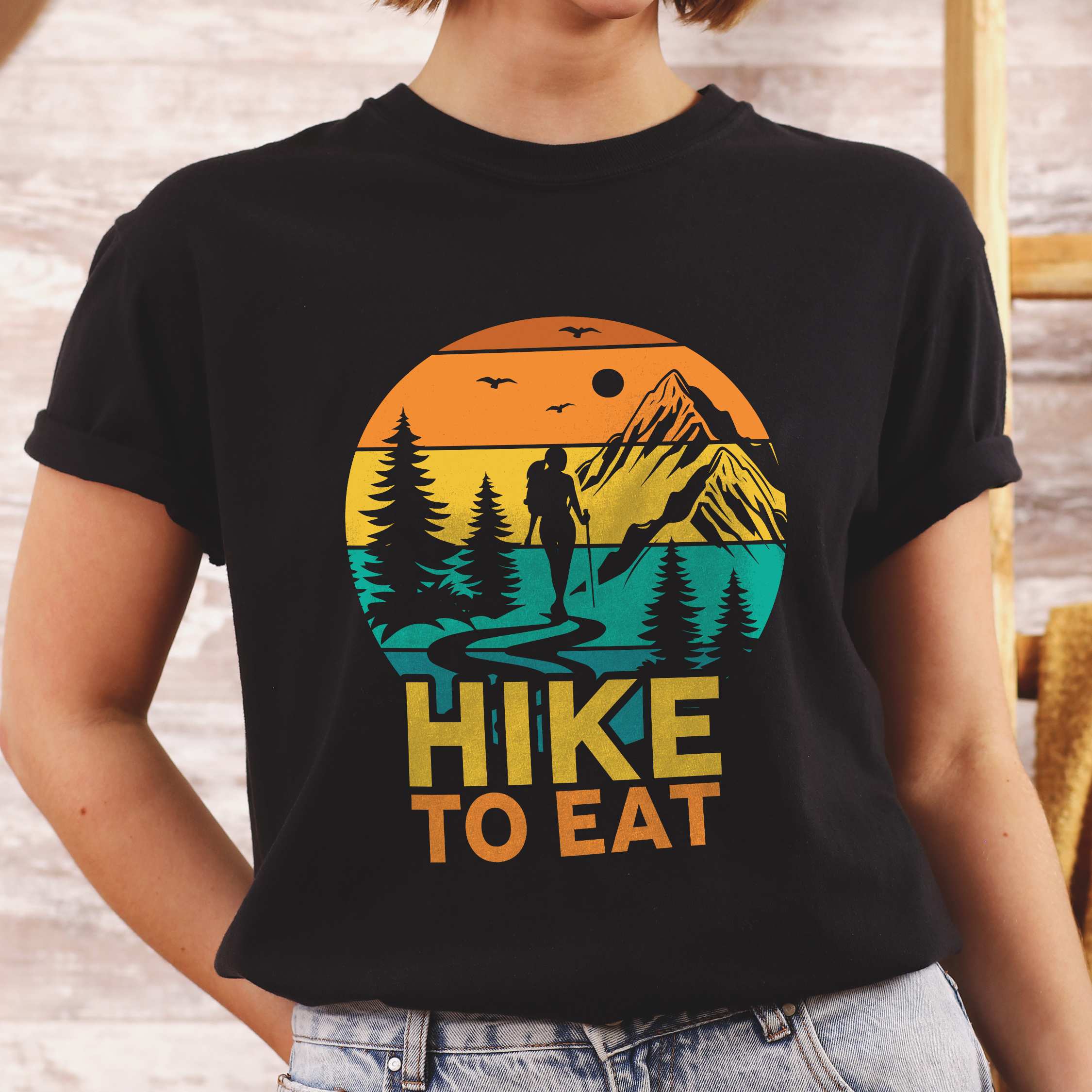 Woman wearing black "Hike to Eat" colored statement tee with bold typography, mountain, sunrise, perfect for adventure driven individuals.