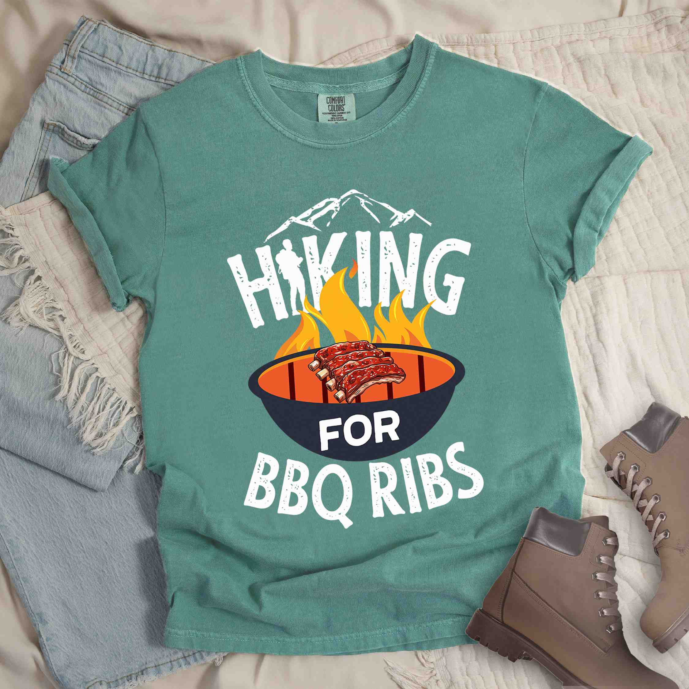 Light green Hiking for BBQ ribs colored vintage tee with bold typography, illustrated grilling bbq ribs, mountains, birds, and bbq enthusiasts