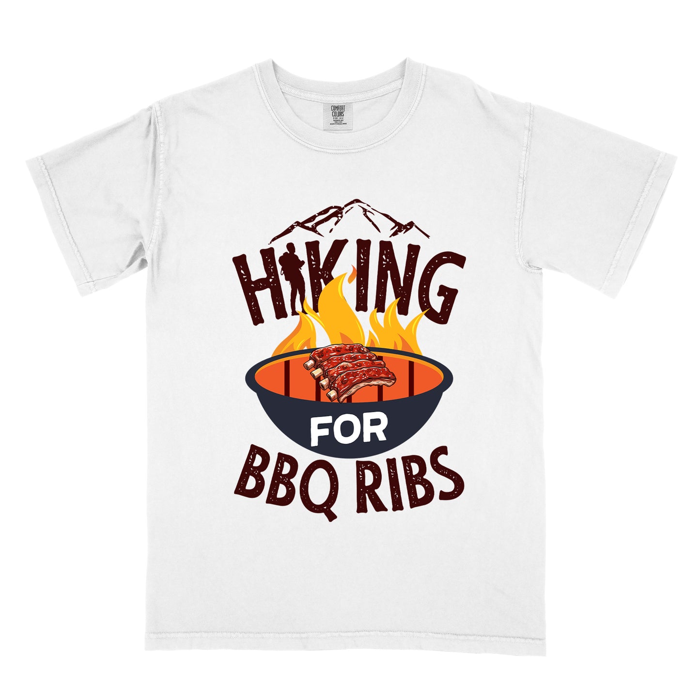 White t-shirt with dark brown distressed text reading "HIKING FOR BBQ RIBS". Mountain silhouettes appear above the word "HIKING". The letter "I" in "HIKING" features a hiker silhouette. Between "HIKING" and "BBQ RIBS" is an illustration of a grill with flames and a rack of ribs cooking. The word "FOR" appears in white on the grill.