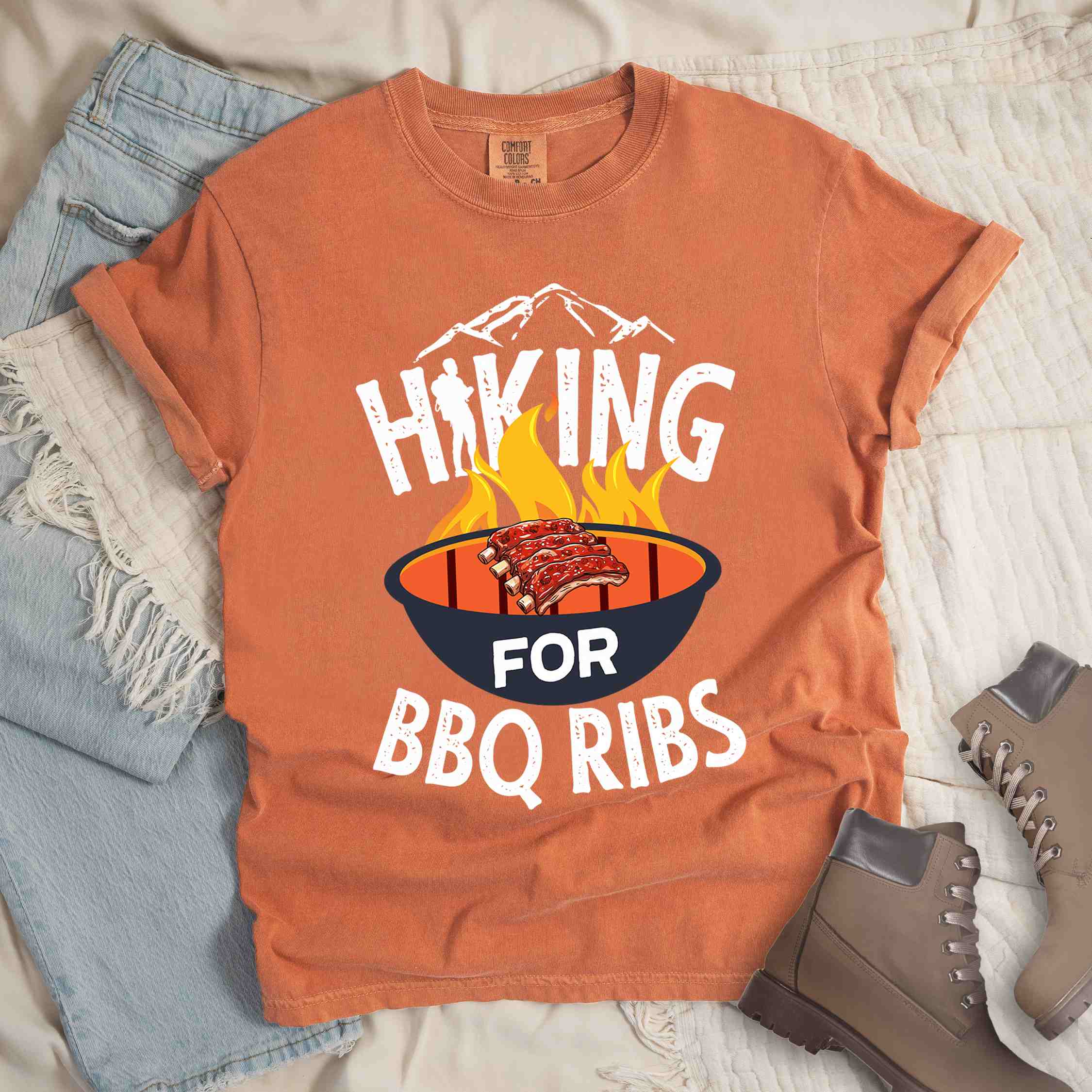 Yam Hiking for BBQ ribs colored vintage tee with bold typography, illustrated grilling bbq ribs, mountains, birds, and bbq enthusiasts