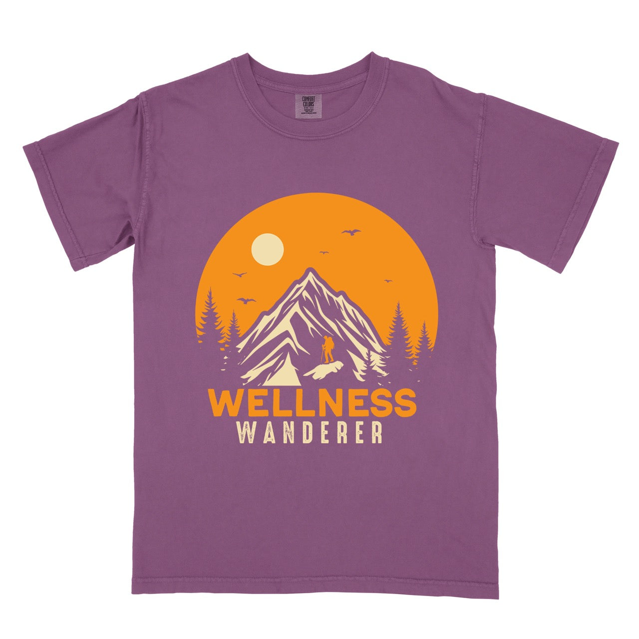 Berry (Purple) Wellness lifestyle vintage tee featuring mountain peak landscape with character silhouette at summit orange sunset circle flying birds pine trees and bold Wellness Wanderer typography on Comfort Colors shirt for nature lovers seeking balance