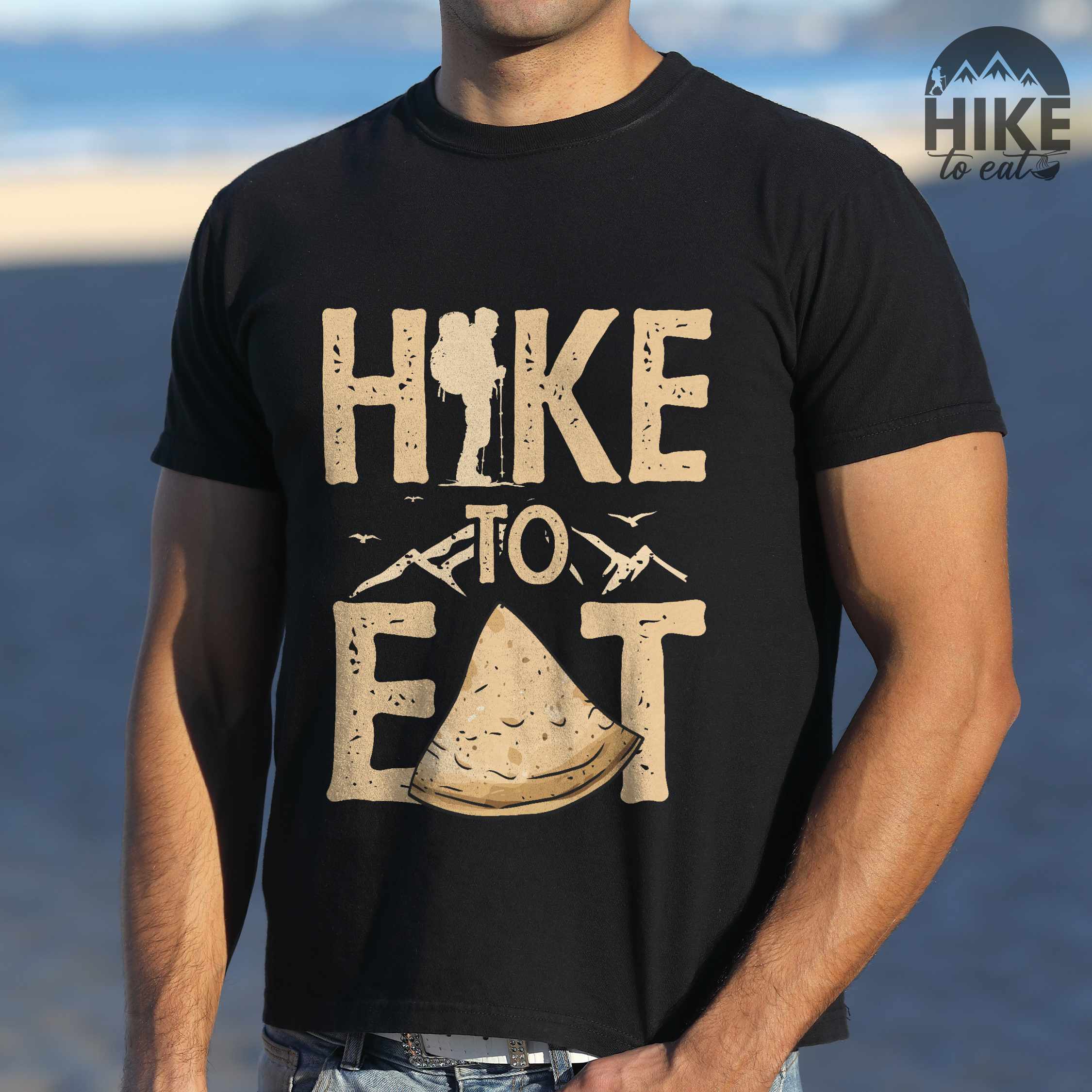 Man wearing black "Hike to Eat" colored statement tee with bold typography, mountain, illustrated tortilla, perfect for tortilla lovers.