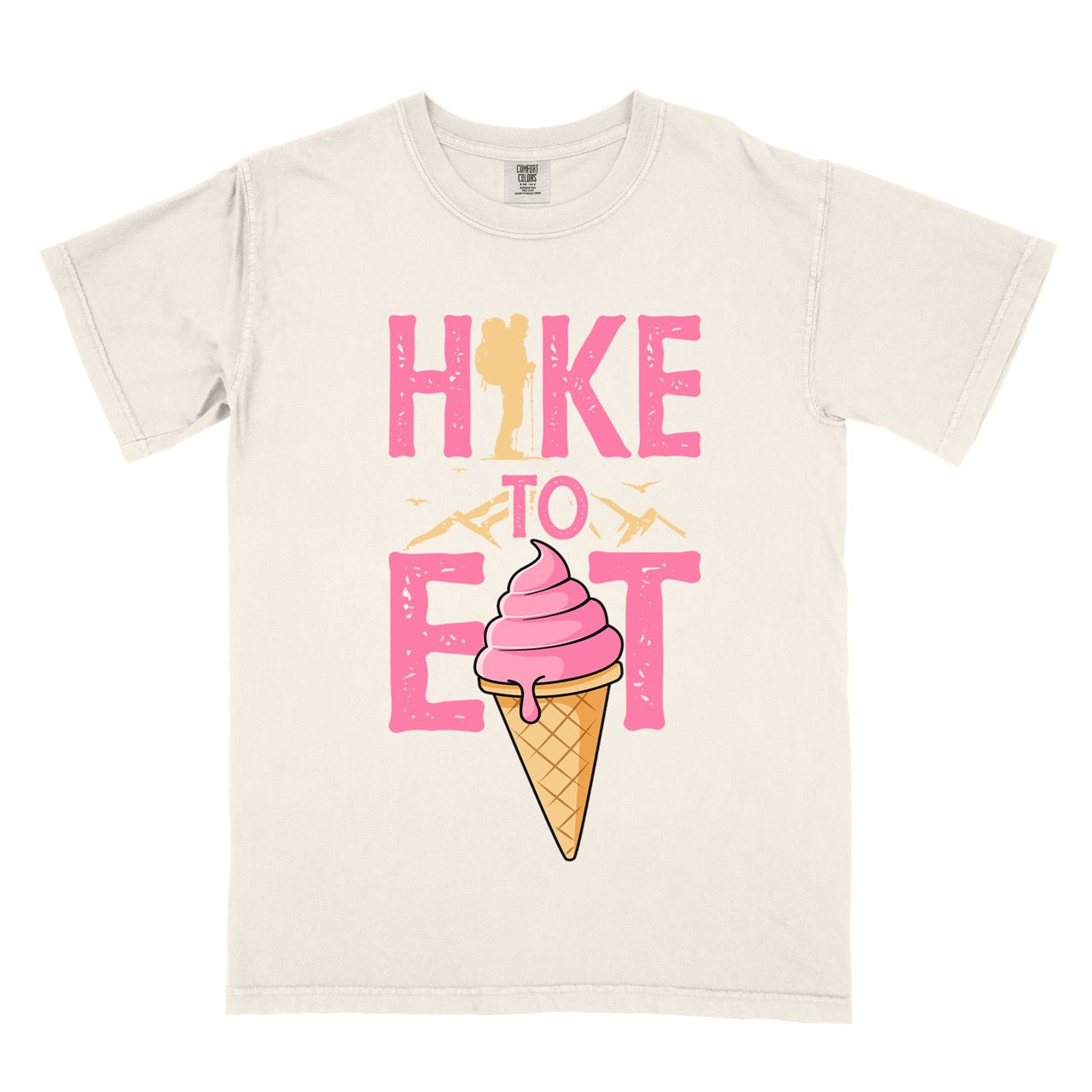 Ivory (beige) Hike to Eat brand logo t-shirt with distressed pink typography, hiker silhouette integrated into letters, mountain peaks, flying birds, and soft-serve ice cream cone illustration for dessert-loving outdoor enthusiasts