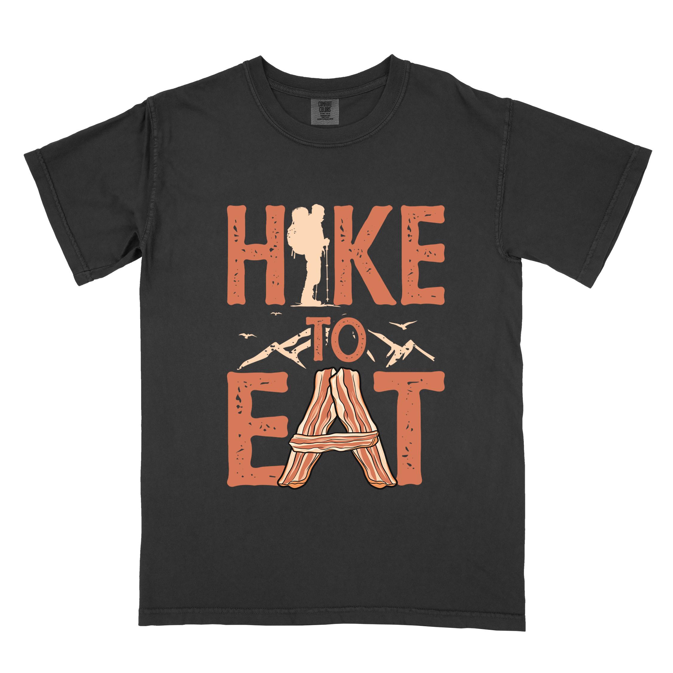 Black "Hike to Eat" colored statement tee with bold typography, mountain, illustrated slices of bacon, and backpacker for breakfast enthusiasts.