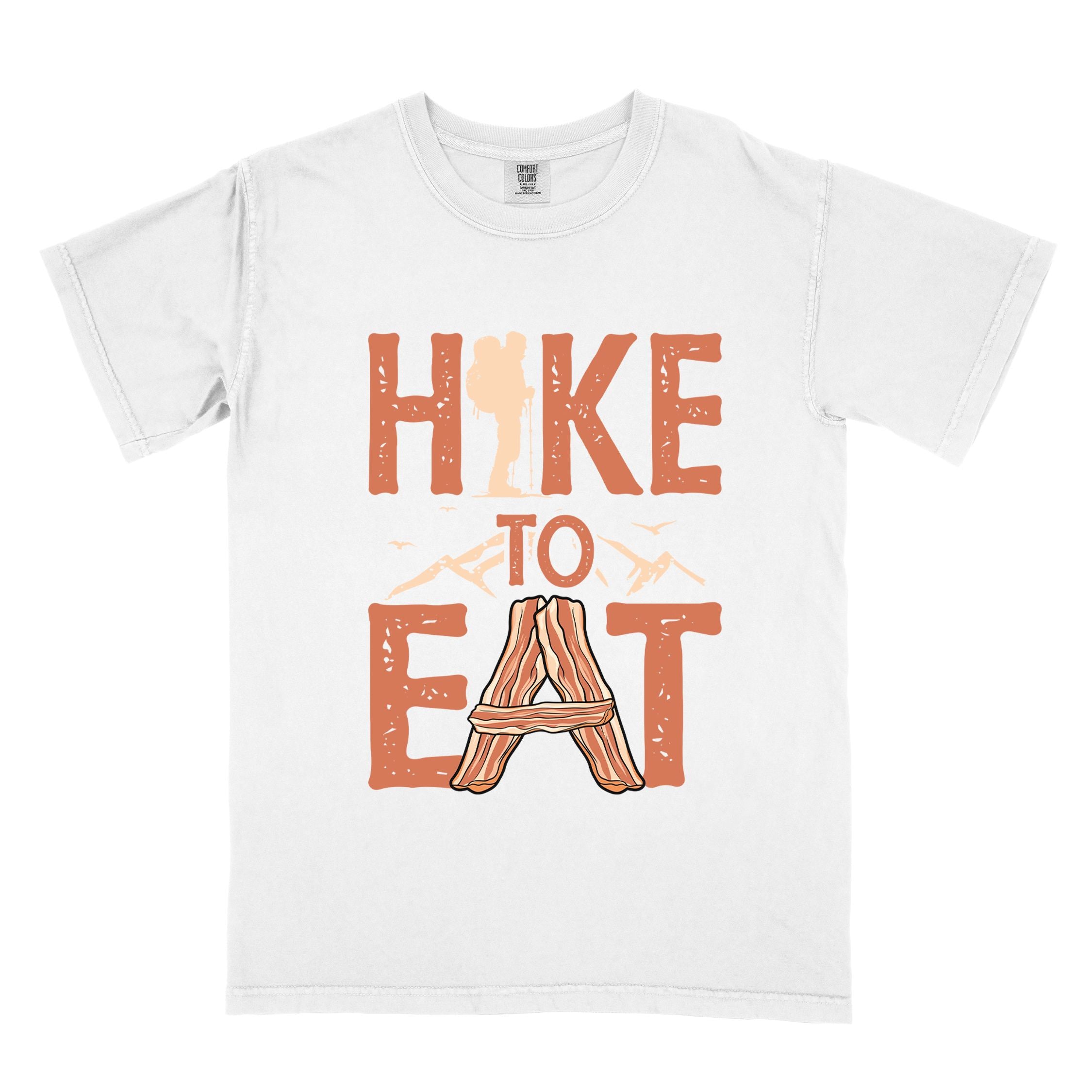 white "Hike to Eat" colored statement tee with bold typography, mountain, illustrated slices of bacon, and backpacker for breakfast enthusiasts.