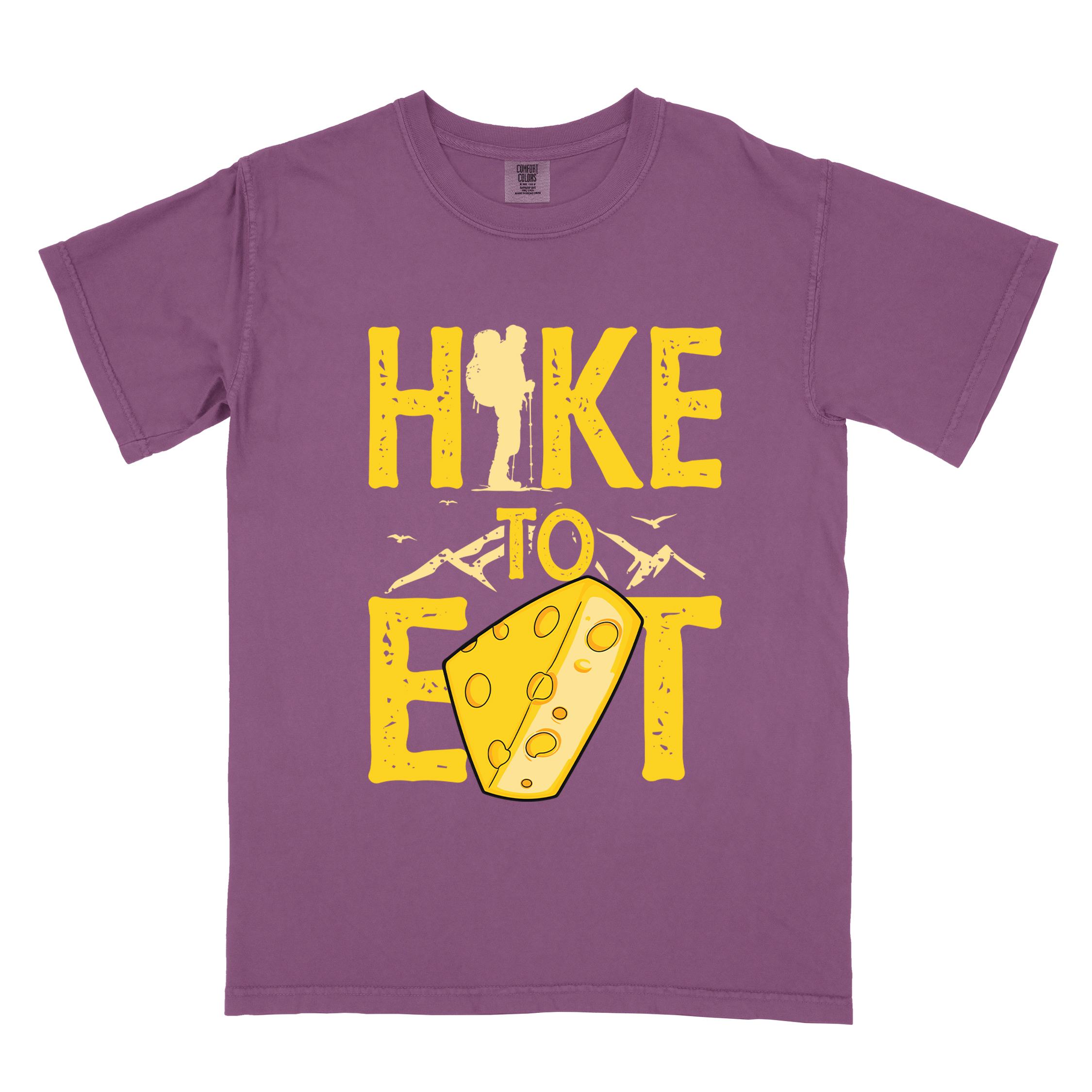 Berry "Hike to Eat" colored statement tee with bold typography, mountain, illustrated slice of cheese, and backpacker for cheese lovers.