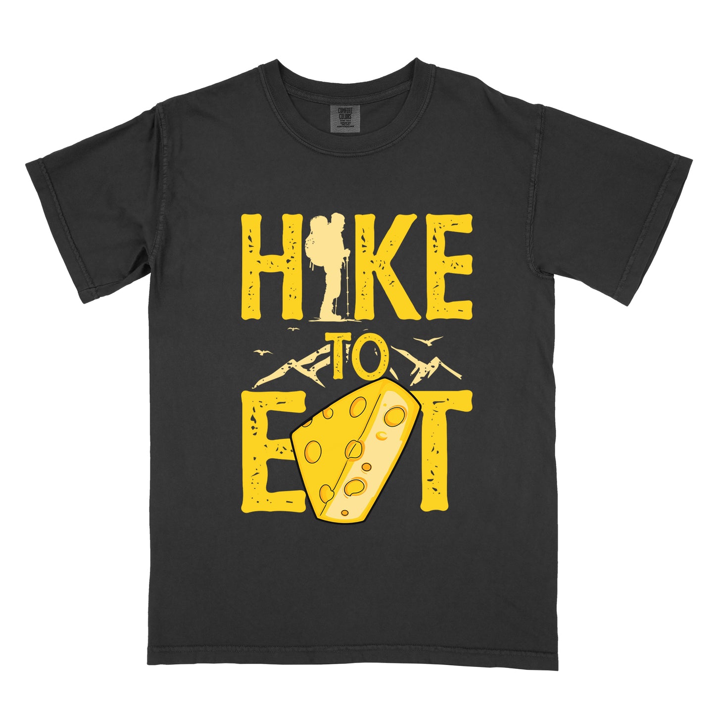 Black t-shirt with yellow distressed text reading "HIKE TO EAT". "HIKE" appears in large yellow letters at the top with a hiker silhouette integrated into the letter "I", "TO" in yellow text with mountain outlines on either side in the middle, and "EAT" in large yellow letters at the bottom with a wedge of Swiss cheese positioned between "E" and "T". Small flying birds appear near "TO". The design connects hiking with eating cheese as motivation.