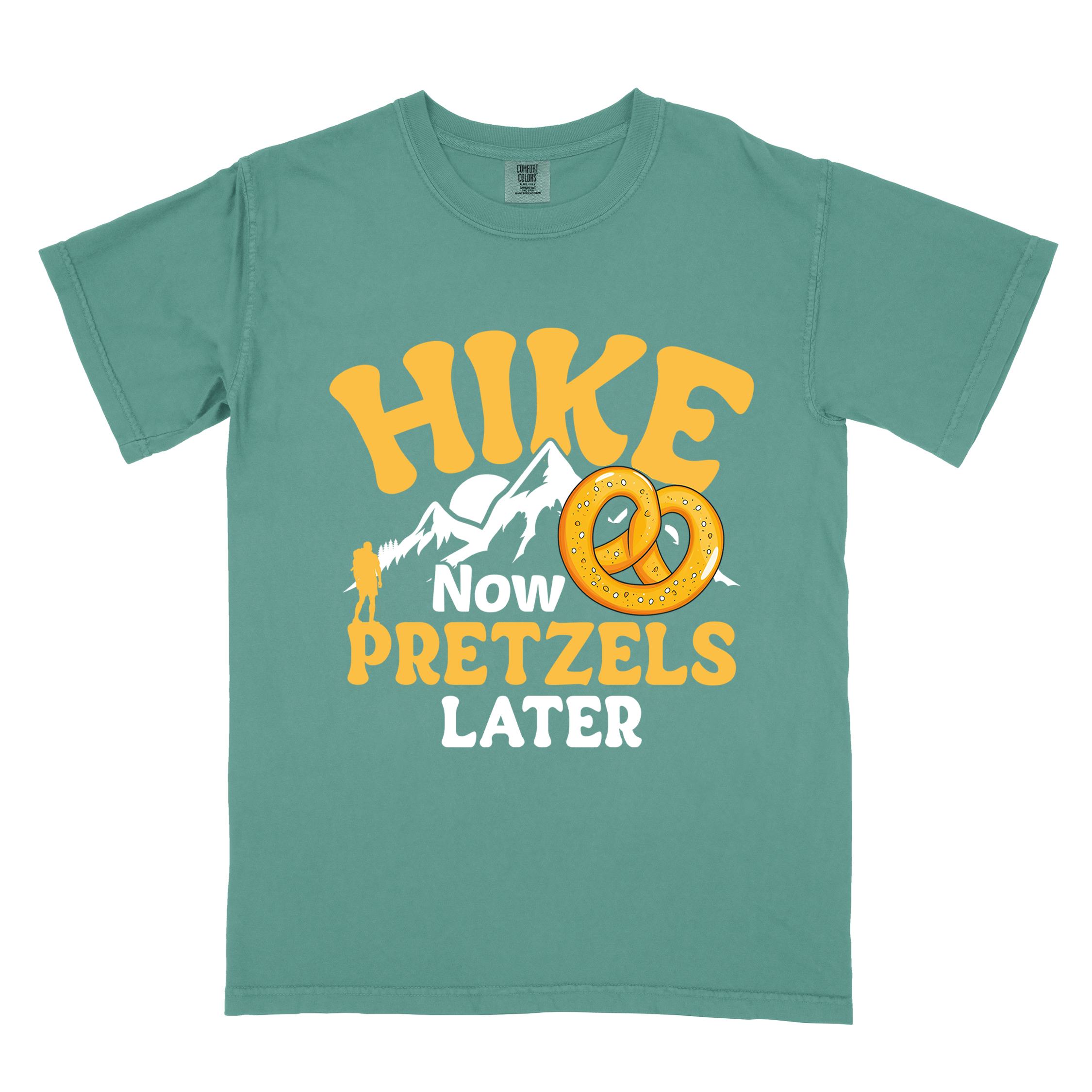 Light green Hike now Pretzels later colored vintage tee with bold typography, mountains, sunrise, and illustrated pretzel for baked pretzel lovers