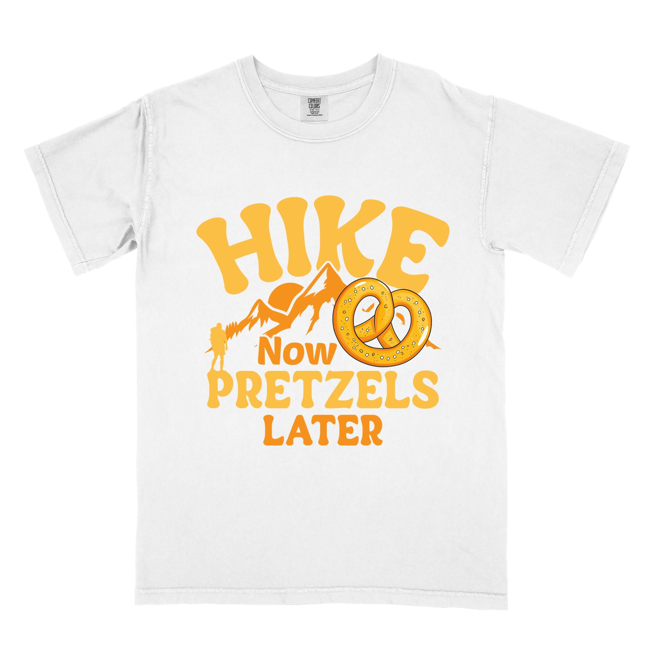 White Hike now Pretzels later colored vintage tee with bold typography, , mountains, sunrise, and illustrated pretzel for baked pretzel lovers
