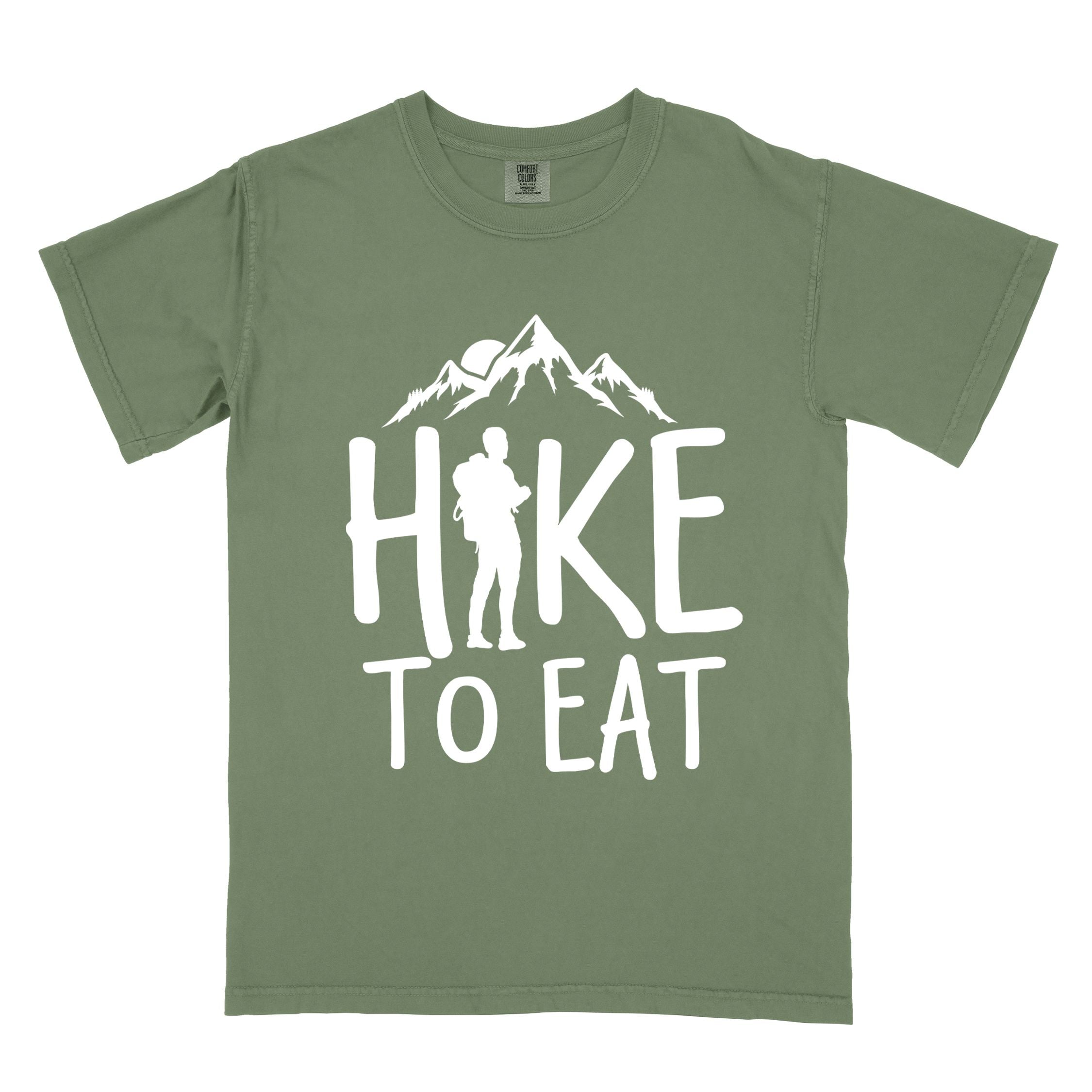 Moss "Hike to Eat" colored statement tee with bold typography, mountains, birds, sunrise, perfect for food motivated individuals.
