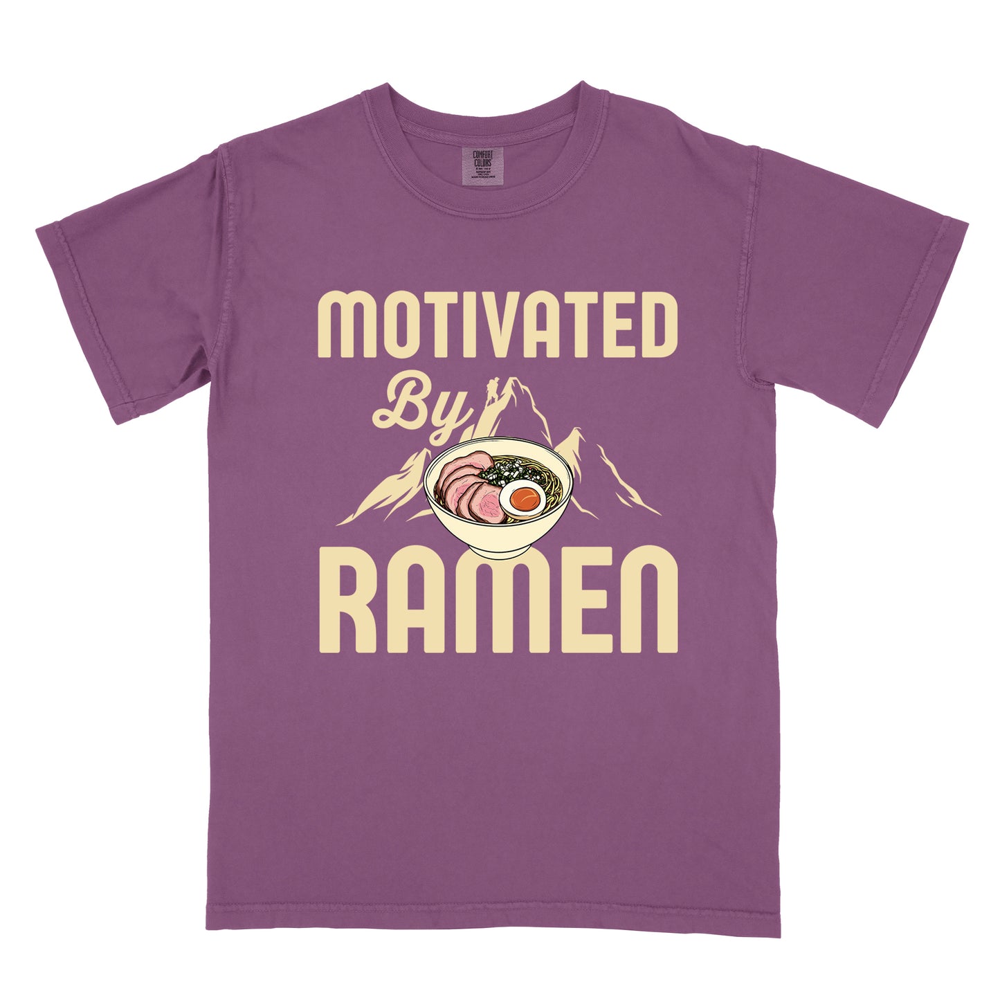 Berry (Dark Violet) t-shirt with cream-colored text reading "MOTIVATED By RAMEN". "MOTIVATED" appears in large letters at the top, "By" in script in the middle, and "RAMEN" in large letters at the bottom. Features a detailed illustration of a ramen bowl with sliced meat, egg, and green onions in the center, positioned over cream-colored mountain silhouettes with a small hiker figure on a peak.