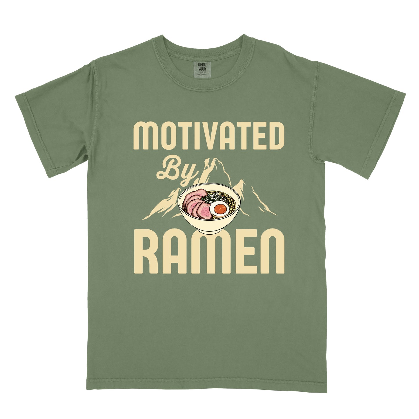 Moss (Dark Green) t-shirt with cream-colored text reading "MOTIVATED By RAMEN". "MOTIVATED" appears in large letters at the top, "By" in script in the middle, and "RAMEN" in large letters at the bottom. Features a detailed illustration of a ramen bowl with sliced meat, egg, and green onions in the center, positioned over cream-colored mountain silhouettes with a small hiker figure on a peak.