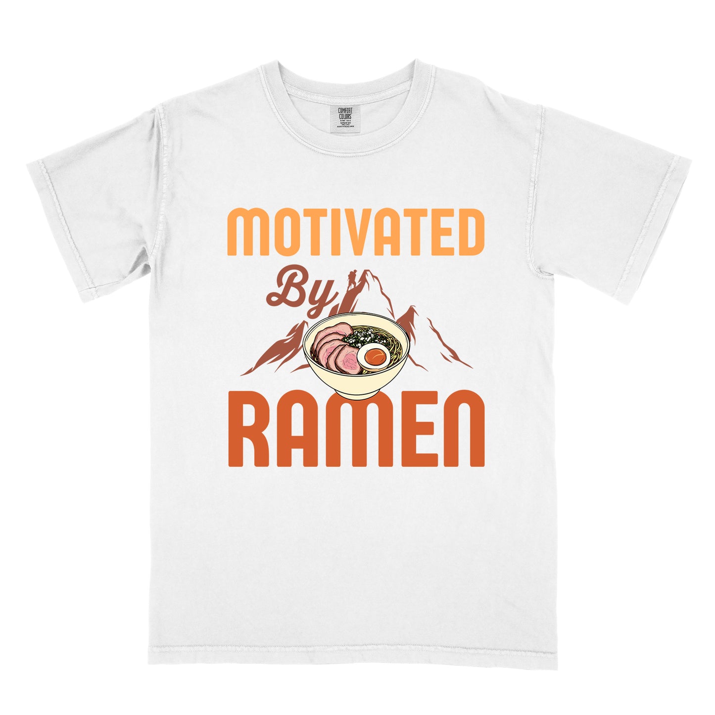 White t-shirt with yellow, orange and brown-colored text reading "MOTIVATED By RAMEN". "MOTIVATED" appears in large letters at the top, "By" in script in the middle, and "RAMEN" in large letters at the bottom. Features a detailed illustration of a ramen bowl with sliced meat, egg, and green onions in the center, positioned over brown-colored mountain silhouettes with a small hiker figure on a peak.