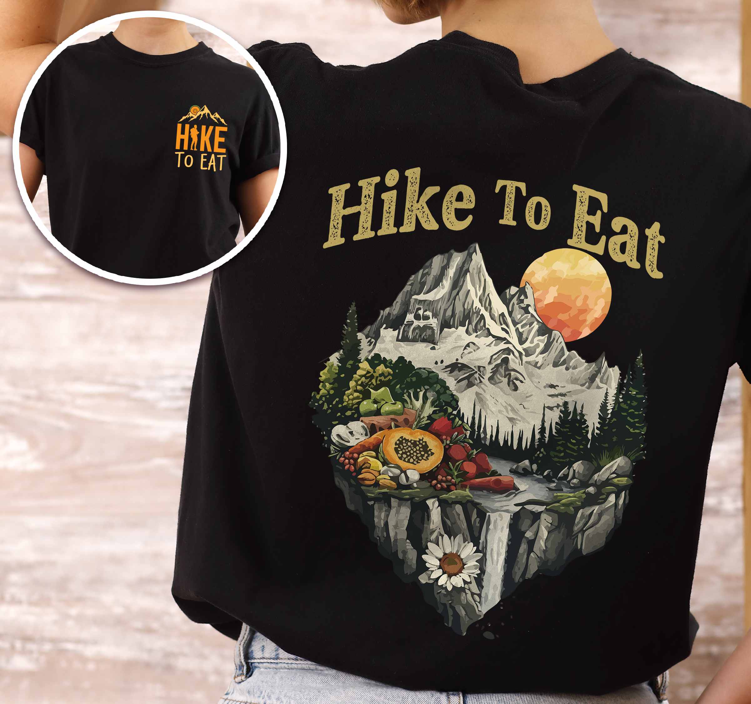 Woman wearing black colored vintage tee with front and back design "Hike to Eat" text in cream lettering, mountains, birds, illustrated fruits, and backpacker for fruit lovers.