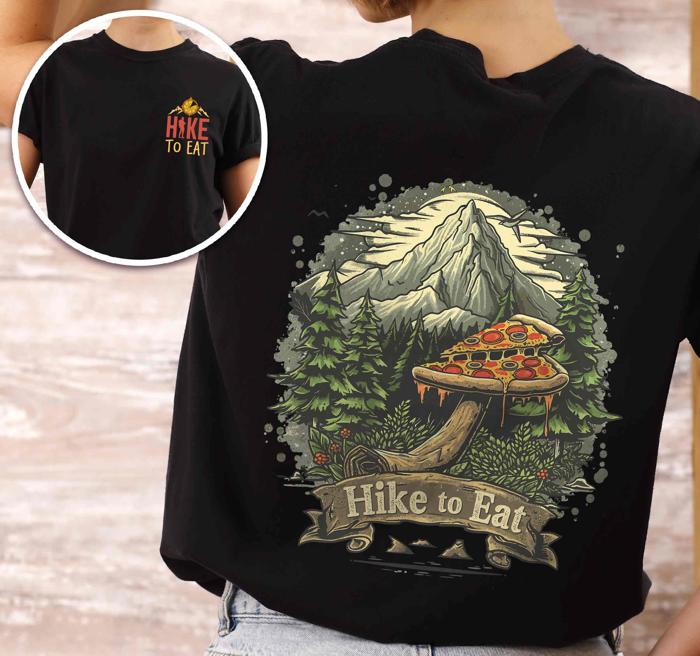 Woman wearing black colored vintage tee with front and back design "Hike to Eat" text in cream lettering, mountains, birds, illustrated pizza slice mushroom top, and backpacker for pizza lovers.