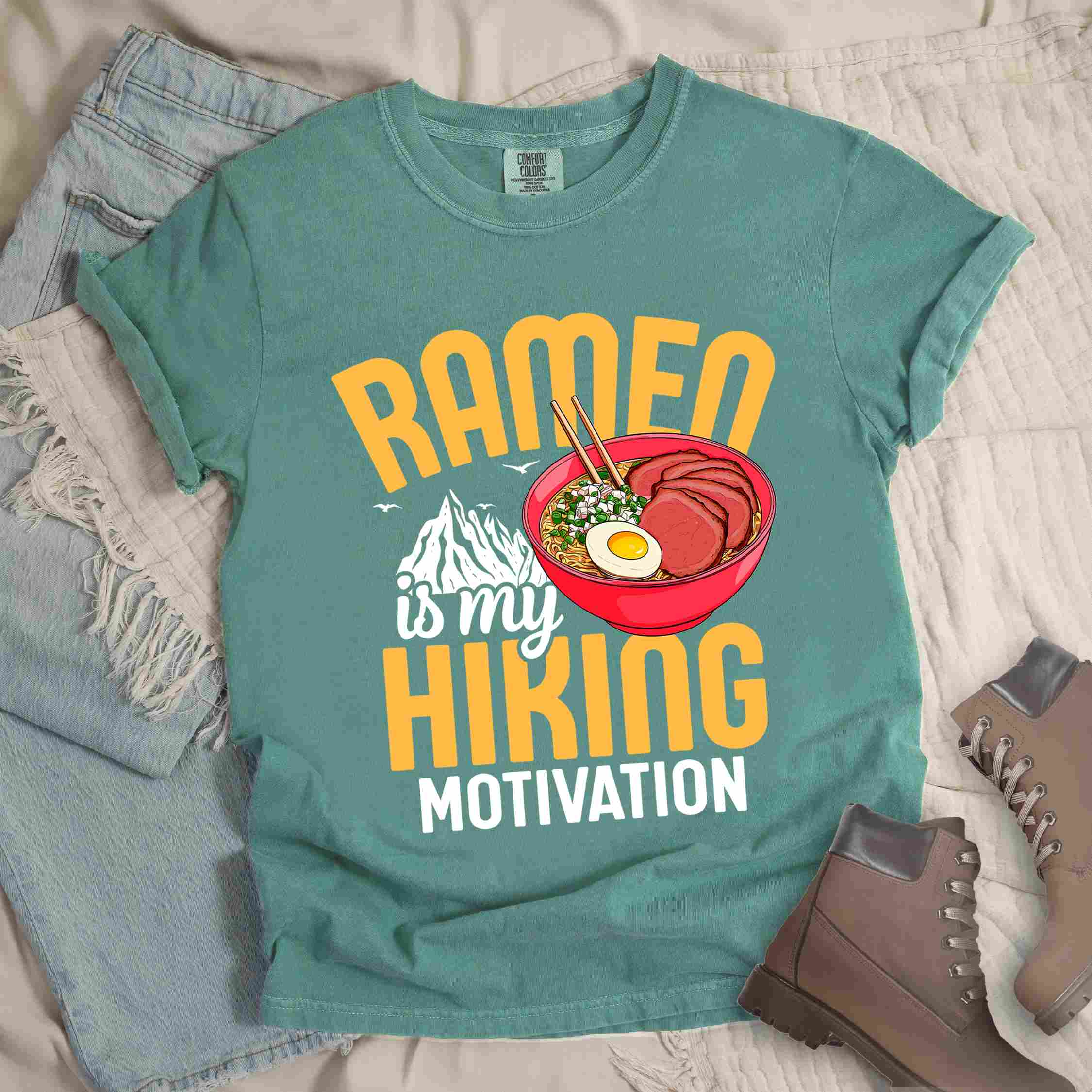 Light green “Ramen is my Hiking motivation” colored vintage tee with bold text, mountain, Illustration of hot ramen. Perfect tee for foodie craving for a bowl of ramen,