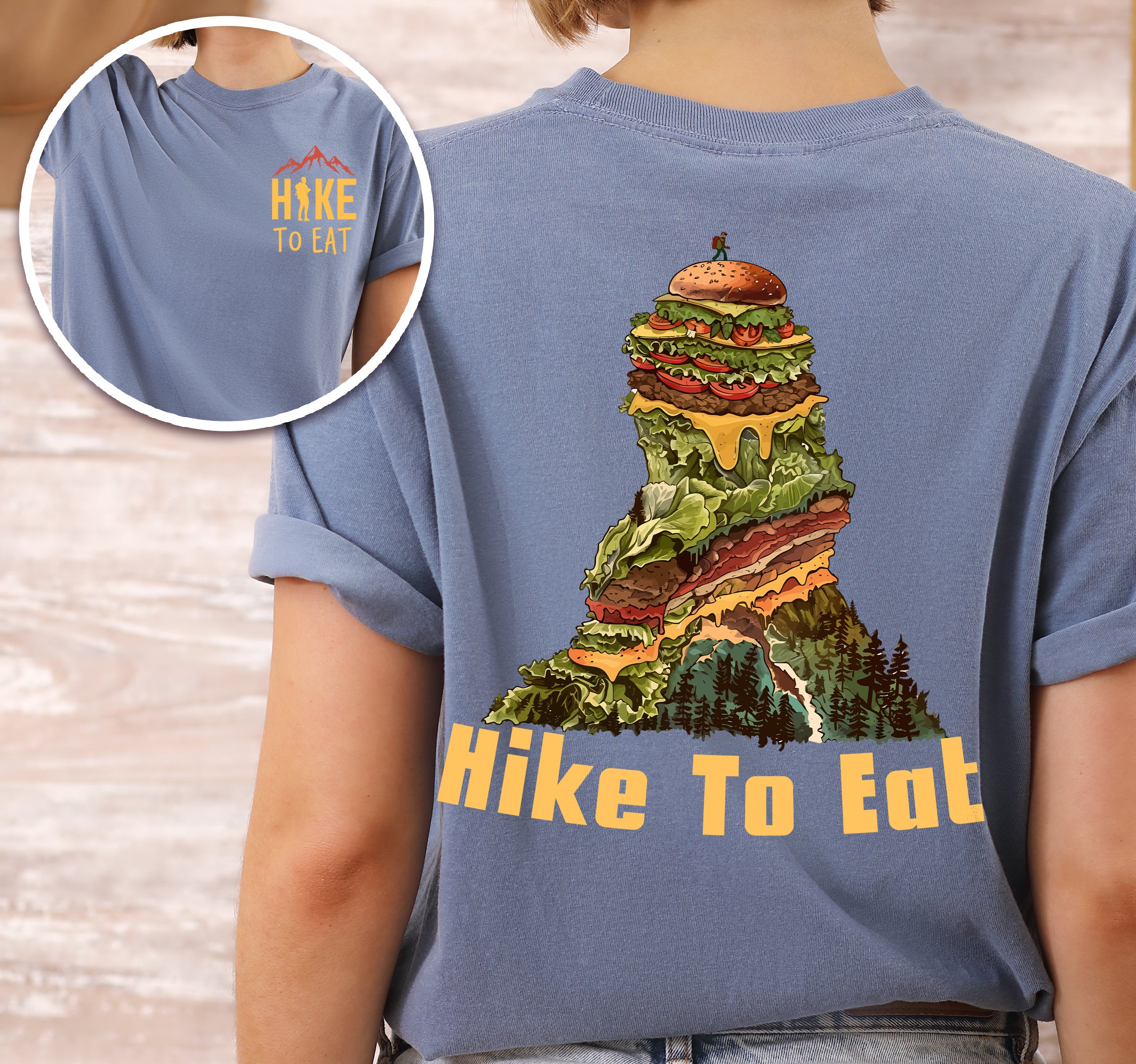 Blue Jean (Denim Blue) Hike to Eat t-shirt front and back view showing small orange chest logo and large back design featuring mountain-shaped burger stack with multiple layers, lettuce, cheese, and pine forest at the base.