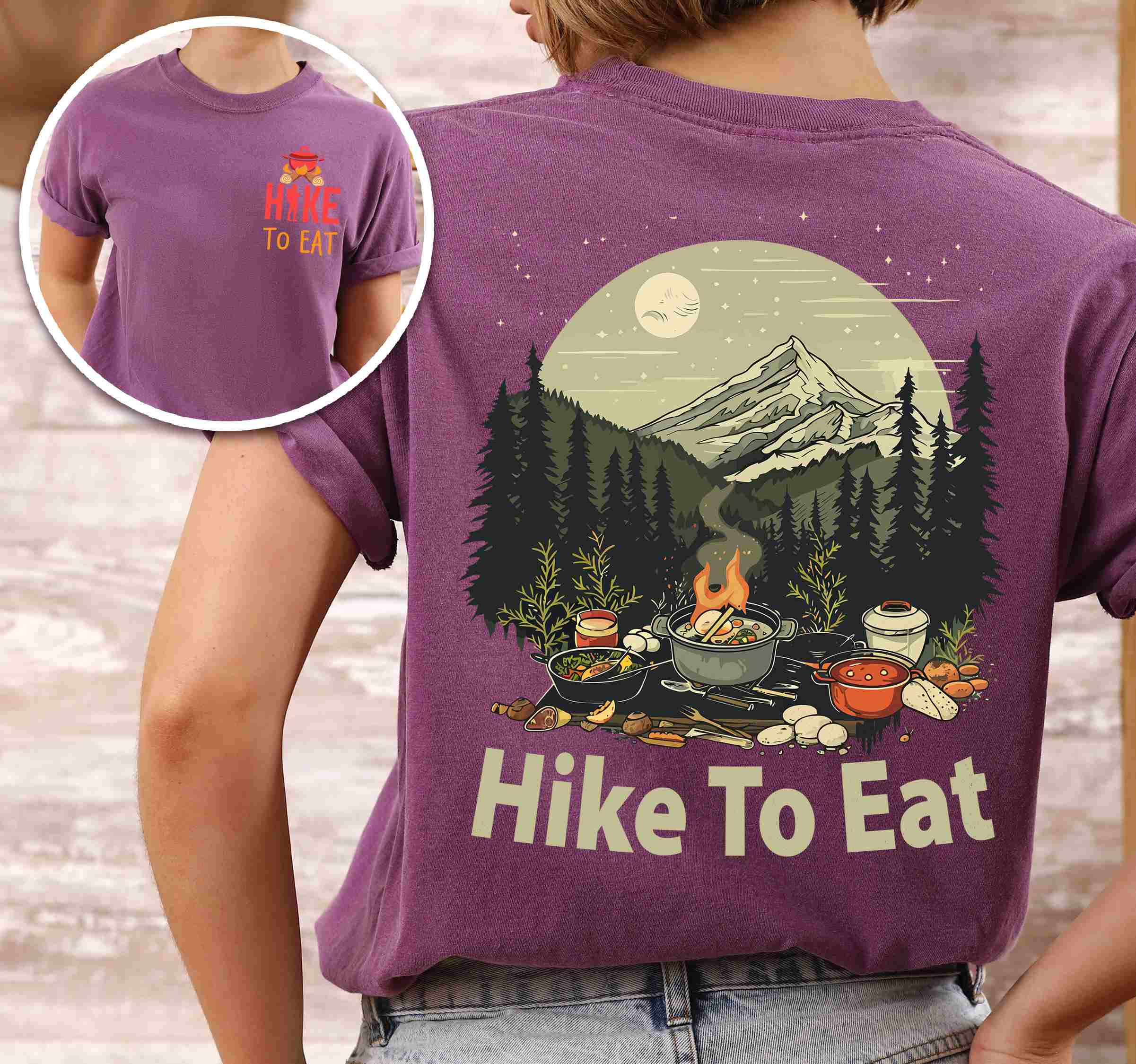 Woman wearing berry "Hike to Eat" text in bold lettering front and back design, mountains, birds, illustrated camping feast, and backpacker for campfire cooking enthusiasts.