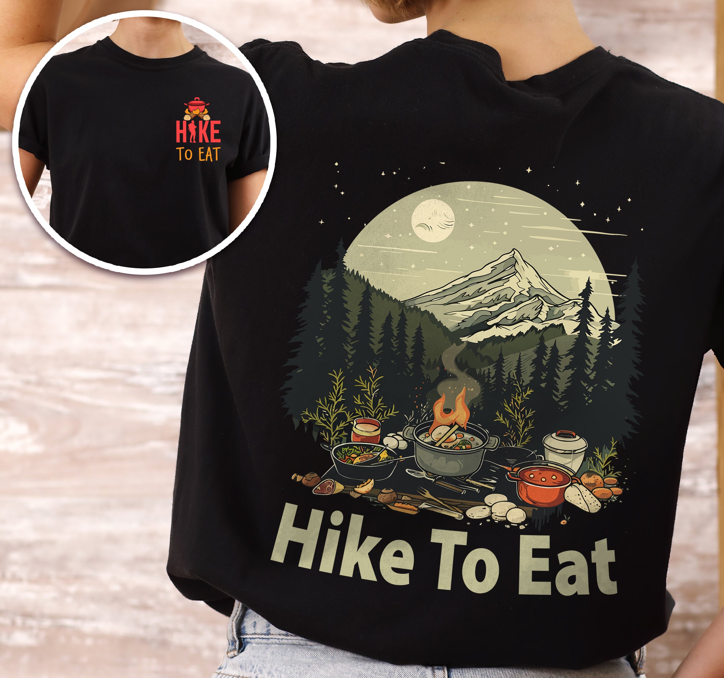 Black Hike to Eat t-shirt front and back view showing small red chest logo and large back design featuring nighttime camping scene with campfire, cooking pots, food, mountains, pine trees, and starry sky with moon.