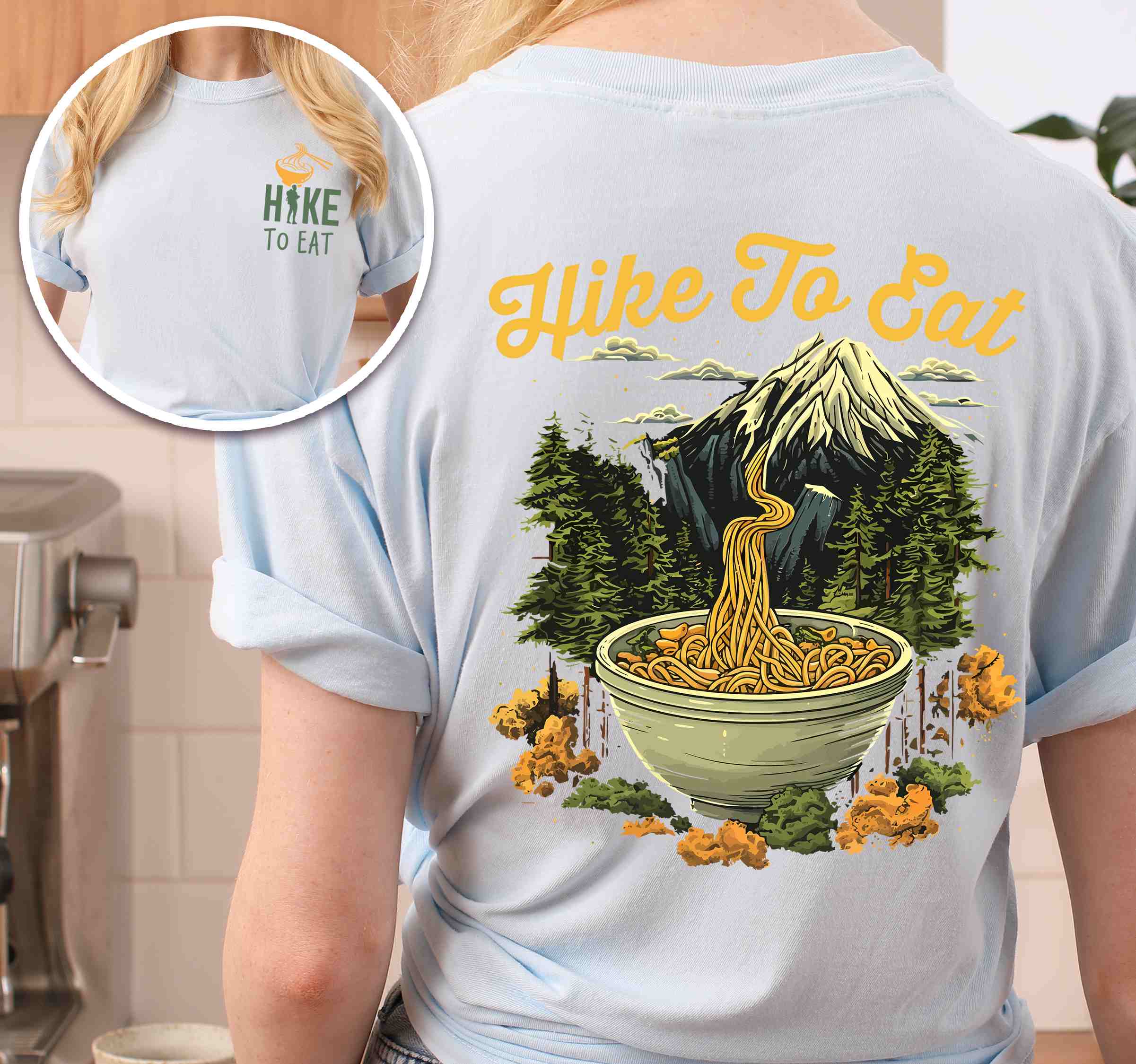 woman wearing chambray "Hike to Eat" text in cream lettering, mountains, birds, illustrated bowl of ramen noodles, and backpacker for ramen lovers.