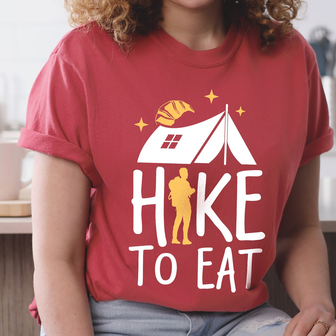 Crimson Hike to Eat brand philosophy vintage tee with white camping tent croissant moon stars character silhouette with backpack integrated into typography on Comfort Colors shirt for food motivated adventurers, outdoor enthusiasts and hikers.