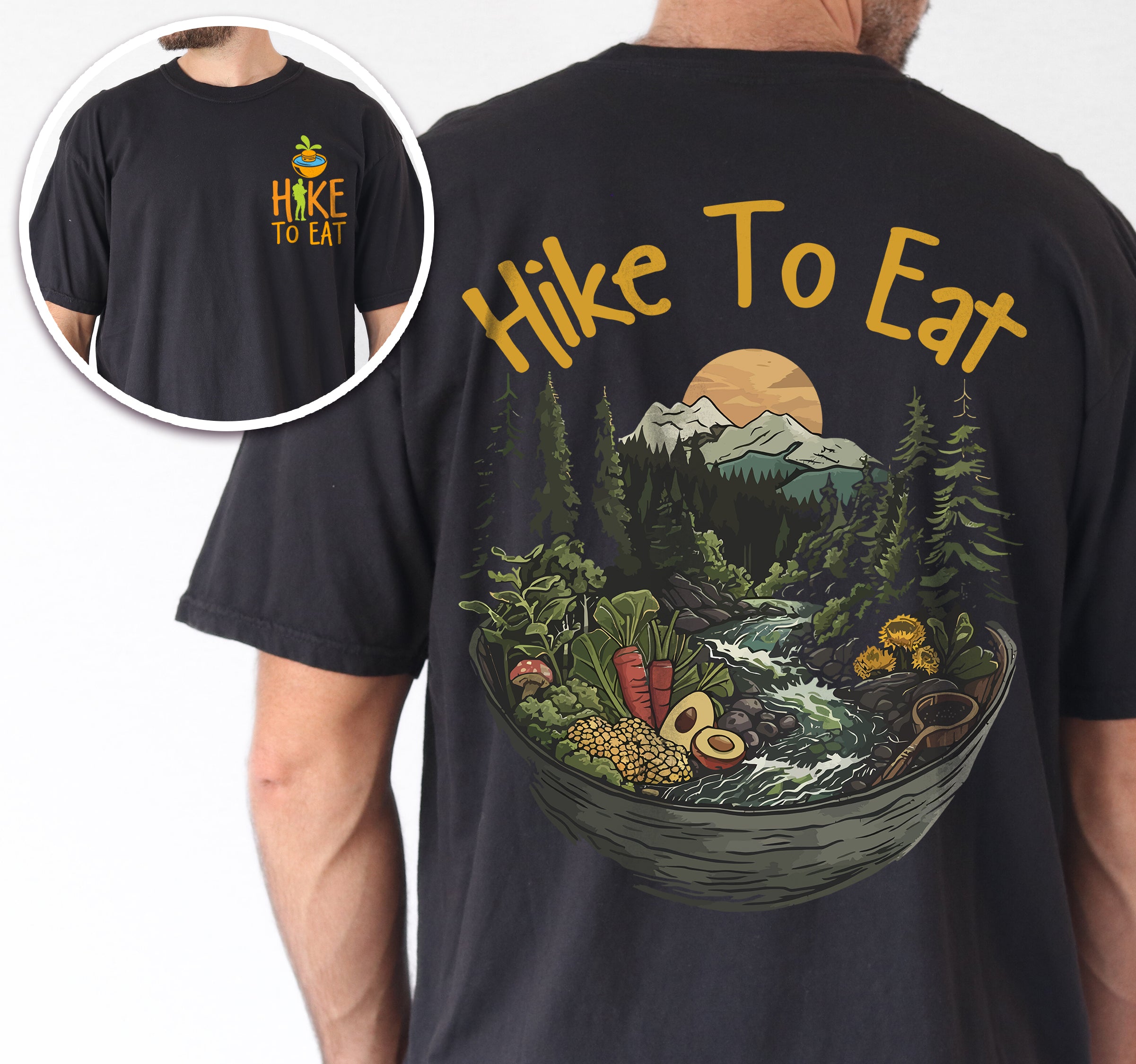 Black Hike to Eat t-shirt front and back view showing small chest design and large back design featuring bowl-shaped mountain landscape with pine trees, waterfall, sunset, and various fresh foods including avocado and vegetables worn by a man.