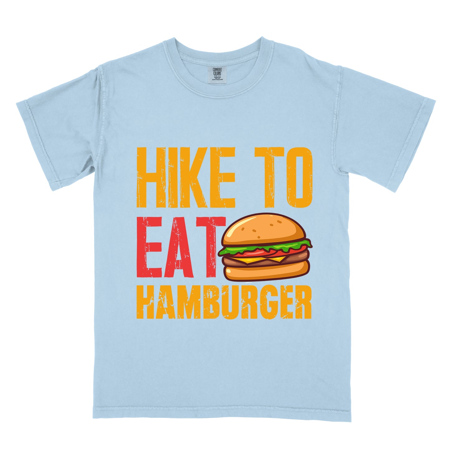 Chambray (Light Blue) t-shirt with distressed text reading "HIKE TO EAT HAMBURGER" arranged in three lines. "HIKE TO" appears in yellow at the top, "EAT" in red in the middle with a colorful hamburger illustration next to it, and "HAMBURGER" in yellow at the bottom. The hamburger graphic shows a bun, meat patty, cheese, lettuce, and tomato.