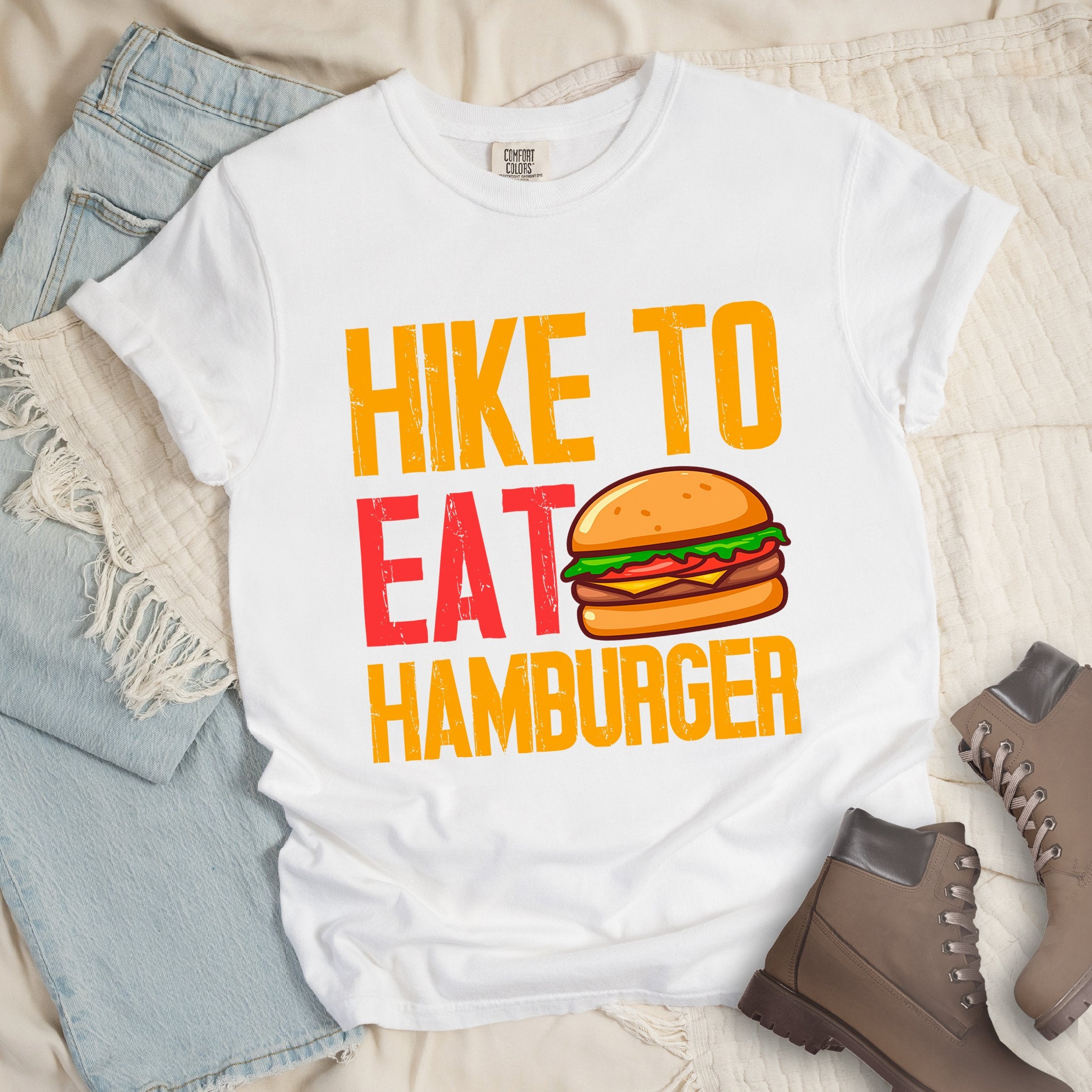White shirt with bold text “Hike to Eat Hamburger” and a cartoon-style hamburger illustration with bun, patty, lettuce, tomato, and cheese.