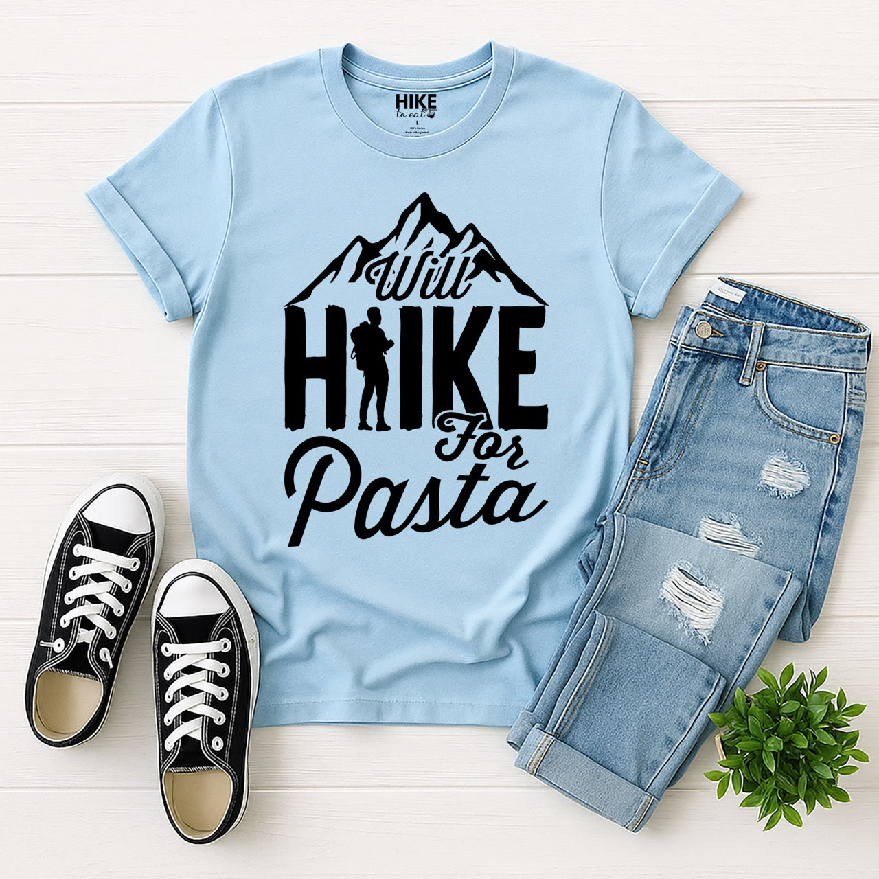 light blue Will Hike for Pasta statement tee with bold typography, mountain peaks, and backpacker silhouette for pasta devotees and hikers with jeans and shoes