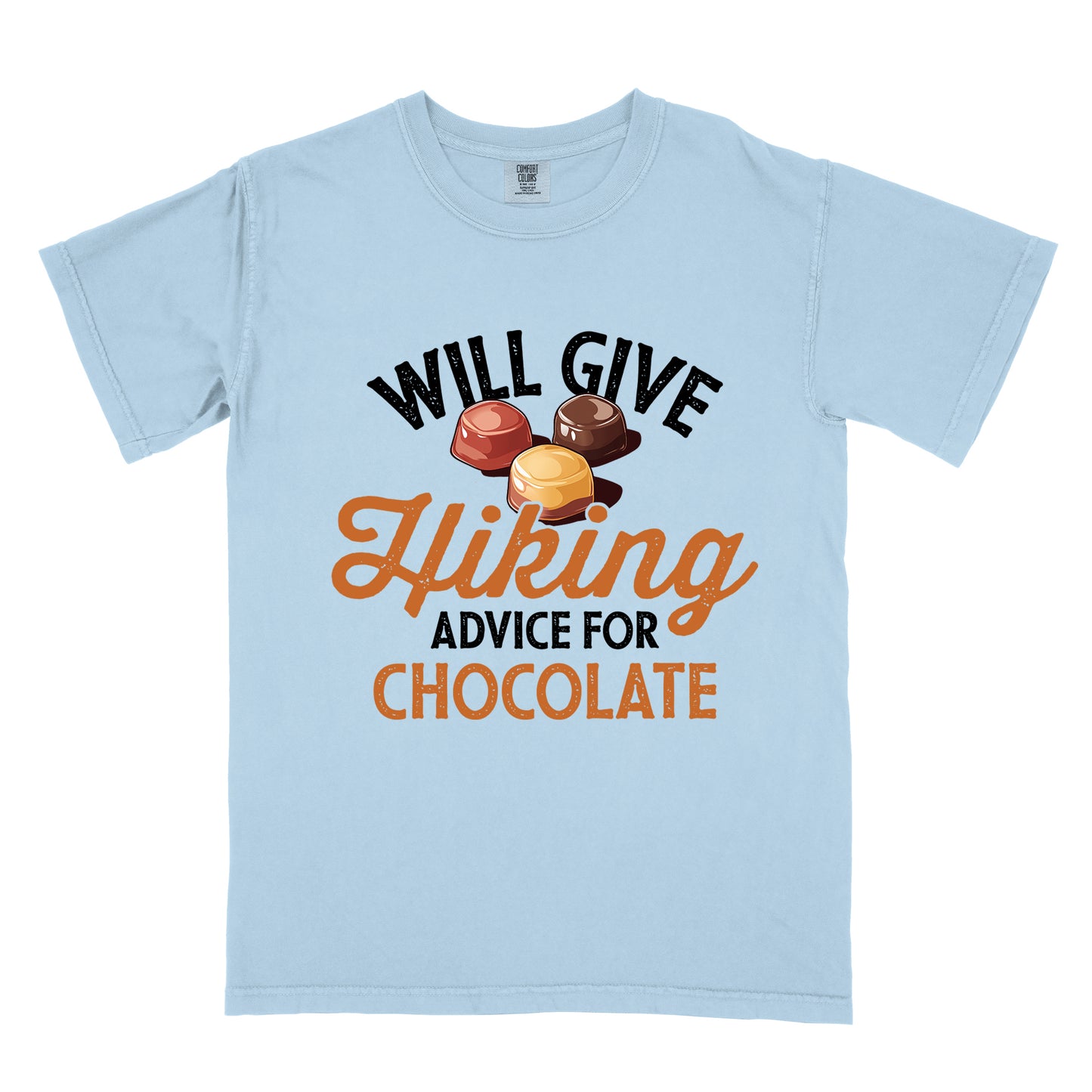 Chambray (Light Blue) t-shirt with text reading "WILL GIVE Hiking ADVICE FOR CHOCOLATE". The words "WILL GIVE" appear in black distressed text at the top, "Hiking" in orange script in the middle, "ADVICE FOR" in black, and "CHOCOLATE" in orange at the bottom. Above the word "Hiking" is an illustration of three chocolate bonbons in different colors (dark, milk, and caramel).