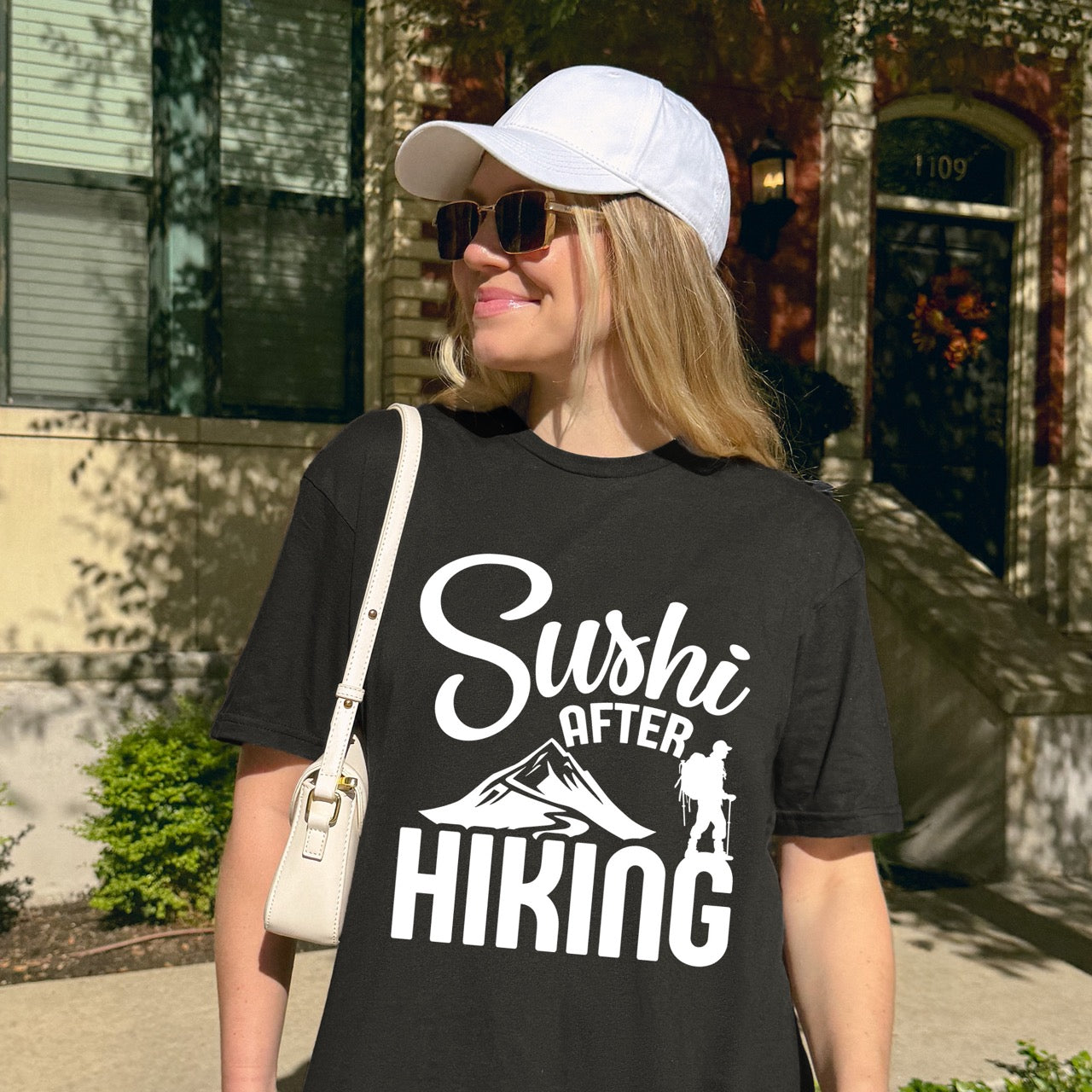 woman wearing black Sushi after Hiking statement tee with elegant script typography, mountain peaks, and hiker silhouette for Japanese food-loving outdoor enthusiasts , foodies and hikers