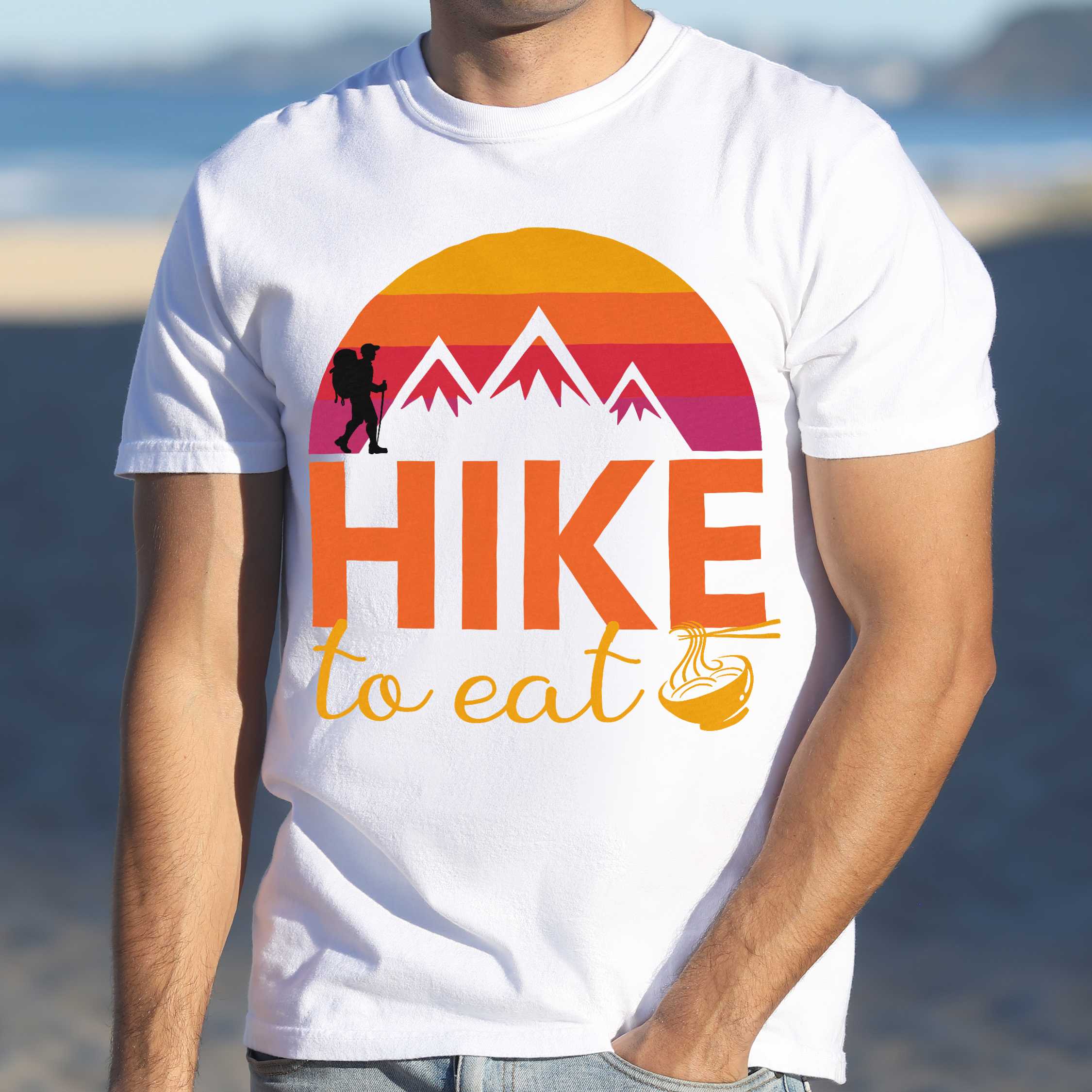 Man wearing white "Hike to Eat" colored vintage tee with bold typography, mountains, sunrise, and backpacker to savor each step along the trail.