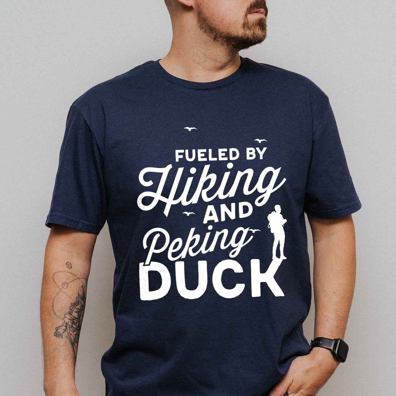 man wearing Navy Fueled by Hiking and Peking Duck statement tee with bold and script typography, flying birds, and hiker silhouette for Chinese food-loving outdoor enthusiasts, hikers and foodies