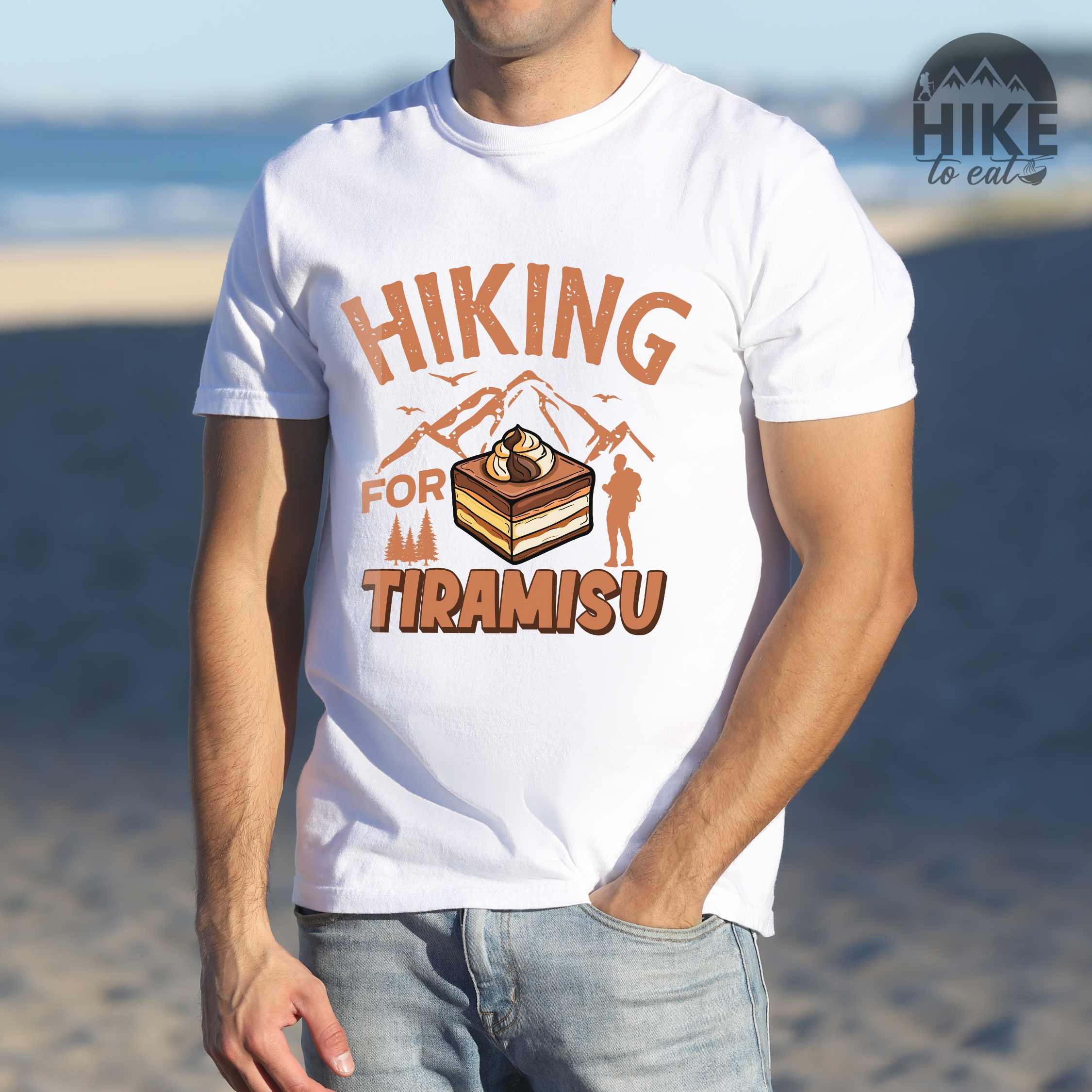 Man wearing white "Hiking for Tiramisu" colored vintage tee with bold typography, mountains, illustrated a serving of Tiramisu, and backpackers with a sweet tooth.
