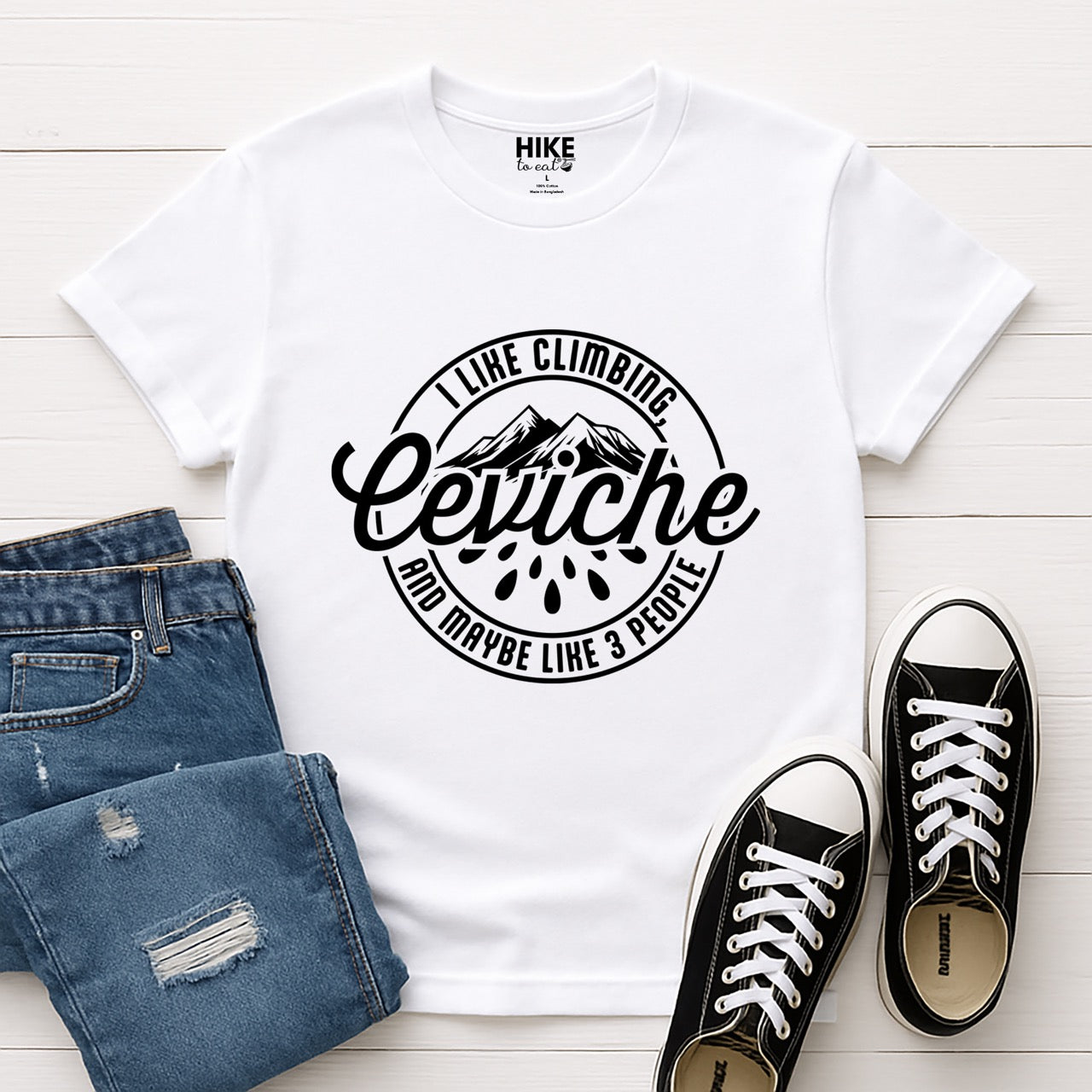 WhiteI like Climbing, Ceviche and maybe 3 People funny introvert statement tee with circular badge design, mountain peaks, and citrus drops for seafood-loving climbers, hikers and foodies laid flat with shoes and pants
