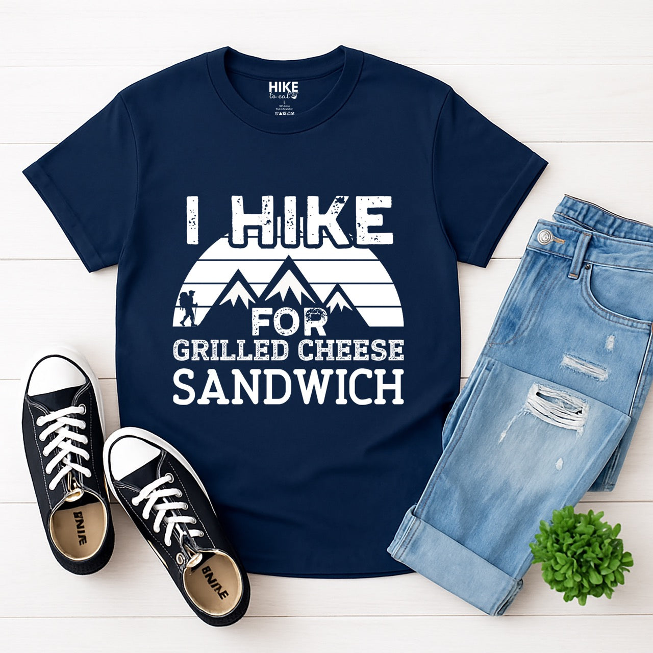 Navy I Hike for Grilled cheese Sandwich statement tee with bold distressed typography, geometric mountain design, and hiker silhouette for grilled cheese-loving outdoor enthusiasts, hikers and foodies laid flat with jeans and shoes