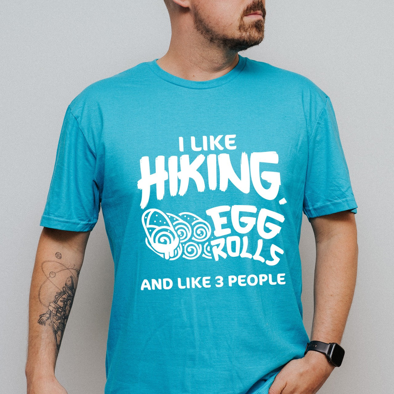 Man wearing Tropical blue I like Hiking, Egg Rolls and like 3 People funny introvert statement tee with bold brushstroke typography and egg roll illustrations for Asian food-loving outdoor enthusiasts, hikers and foodies