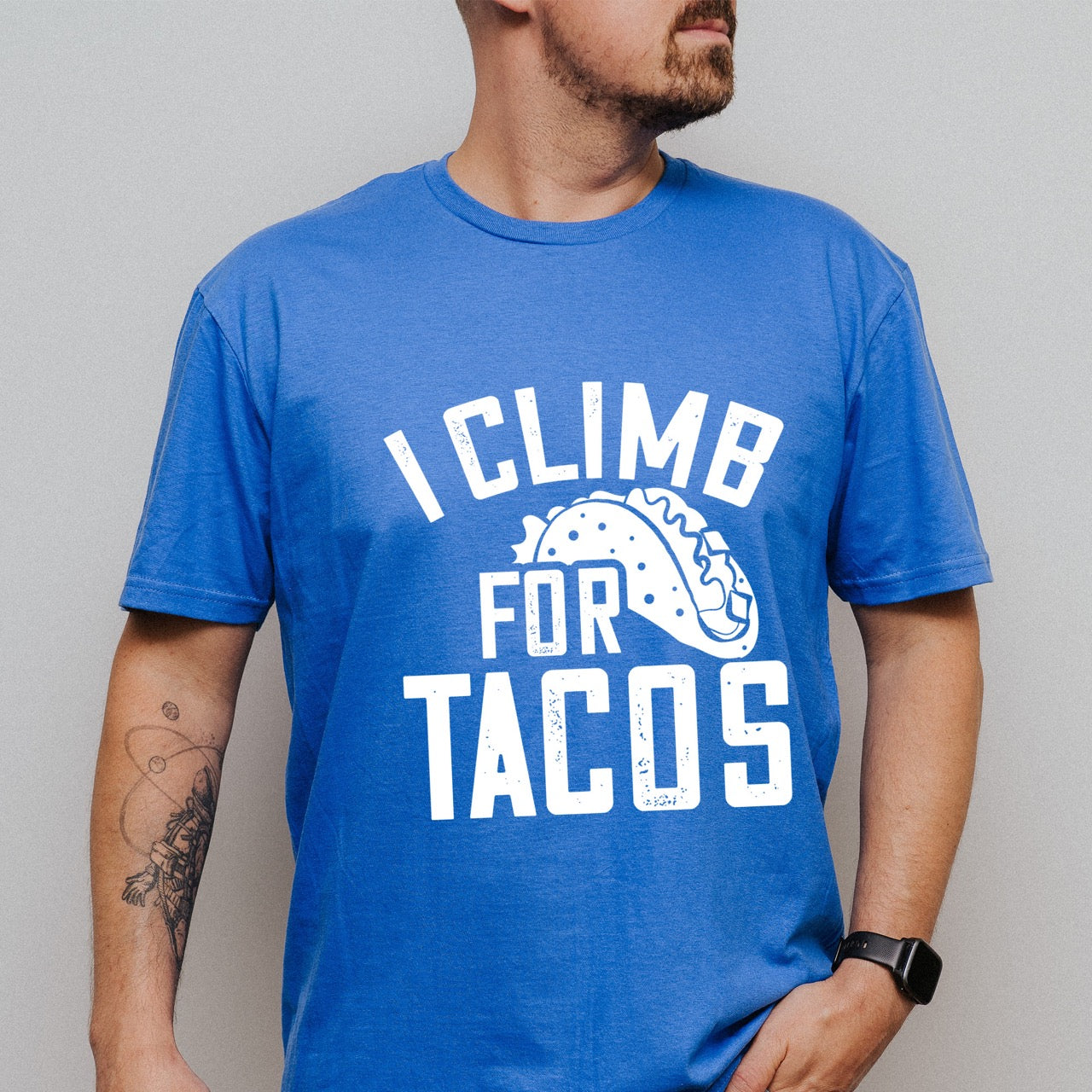 Man wearing Royal I climb for Tacos statement tee with bold distressed curved typography and detailed taco illustration for Mexican food-loving rock climbers and nature hikers.