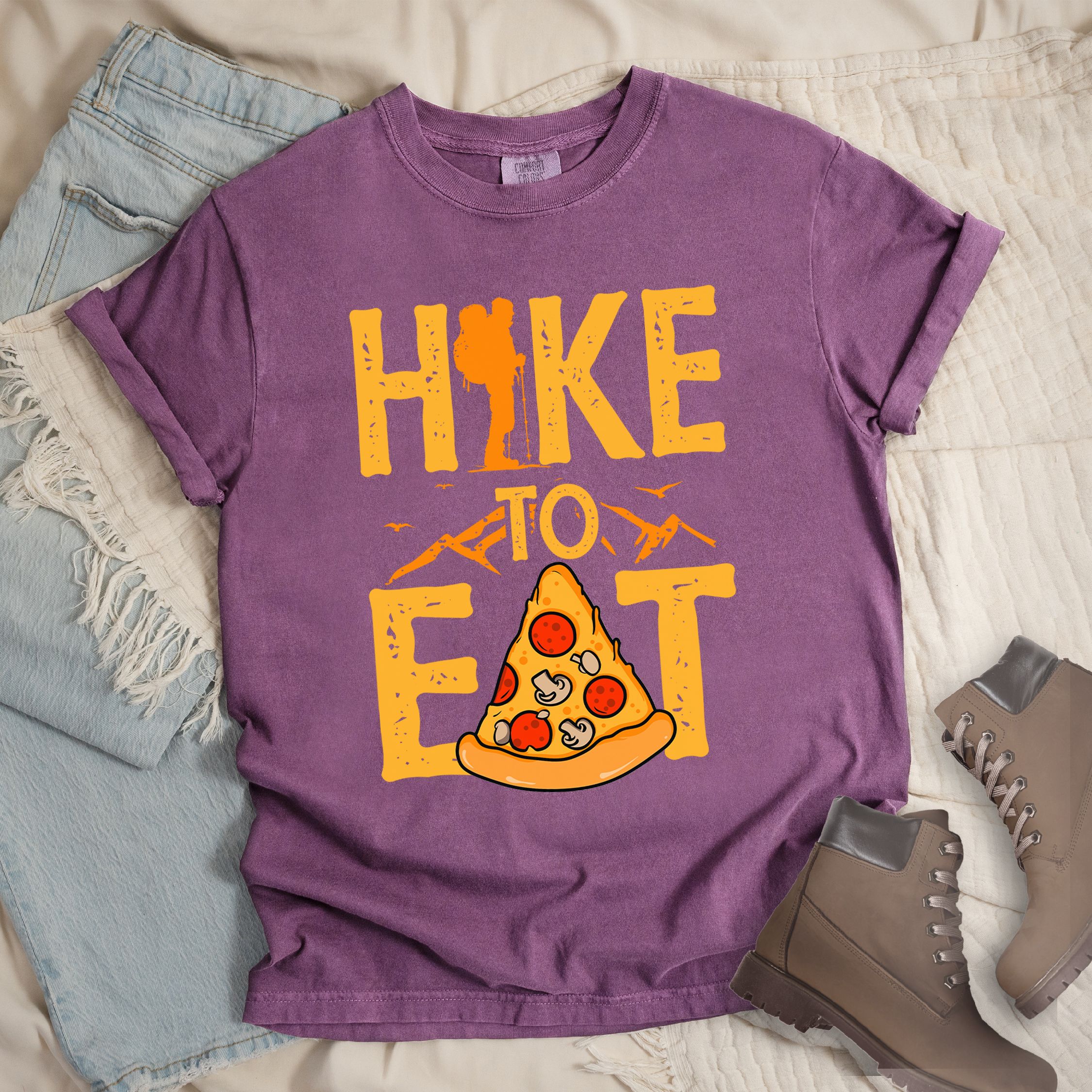 Dark pink shirt with a Hiking design of a slice of pizza and shows 'Hike To Eat' phrase in bold text
