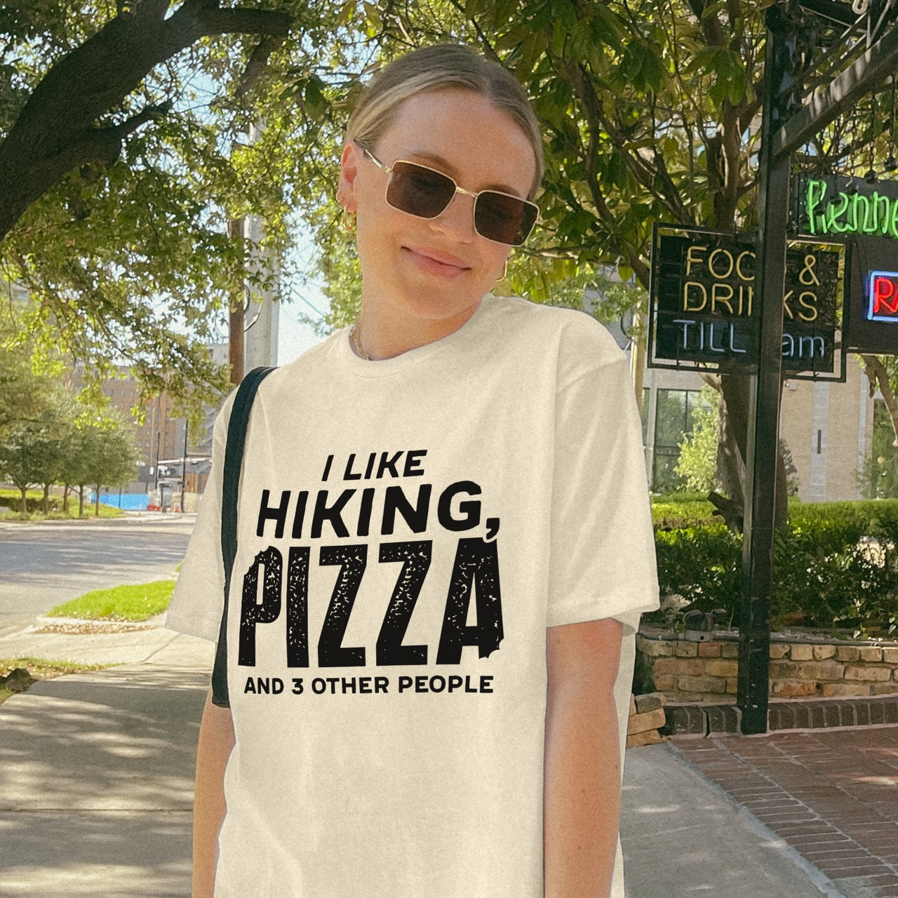 Woman wearing Natural (beige) Motivated by Wontons statement tee with bold distressed typography, mountain peaks, pine trees, and wonton illustration for Chinese food-loving outdoor enthusiasts, hikers and foodies
