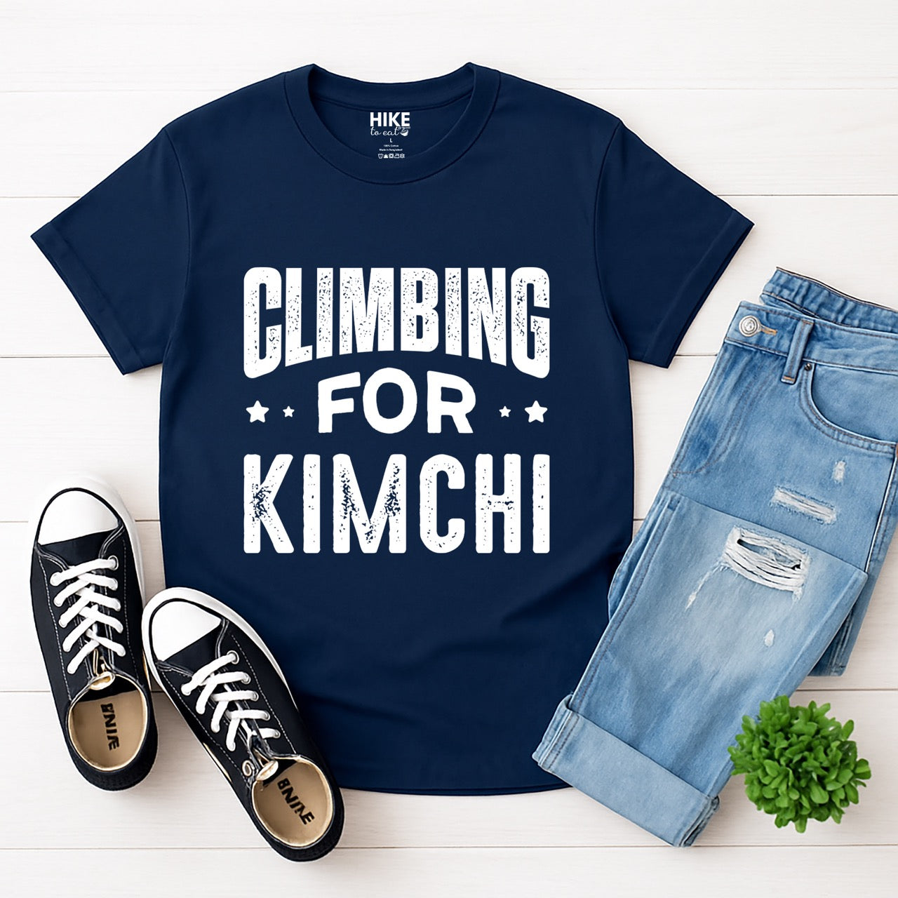 Navy Rock climbing enthusiast gift shirt Climbing For Kimchi with bold curved distressed typography and decorative star accents for Korean food lovers and outdoor athletes who crave fermented vegetables after mountain adventures for climbers, hikers and foodies laid flat with pants and shoes