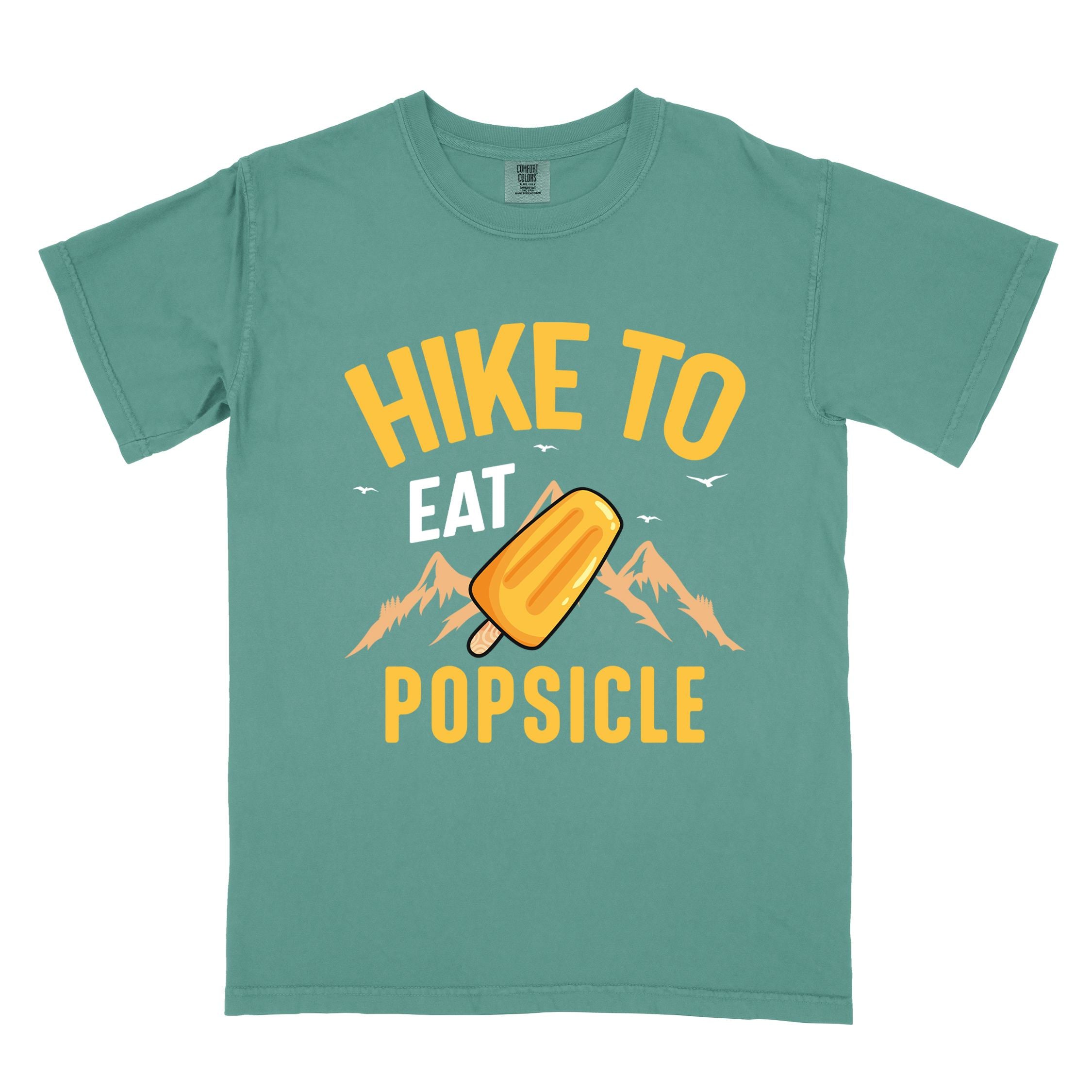 Light green "Hike to Eat Popsicle" colored vintage tee with bold typography, mountains, illustrated flavored popsicle, and backpackers with a sweet tooth.