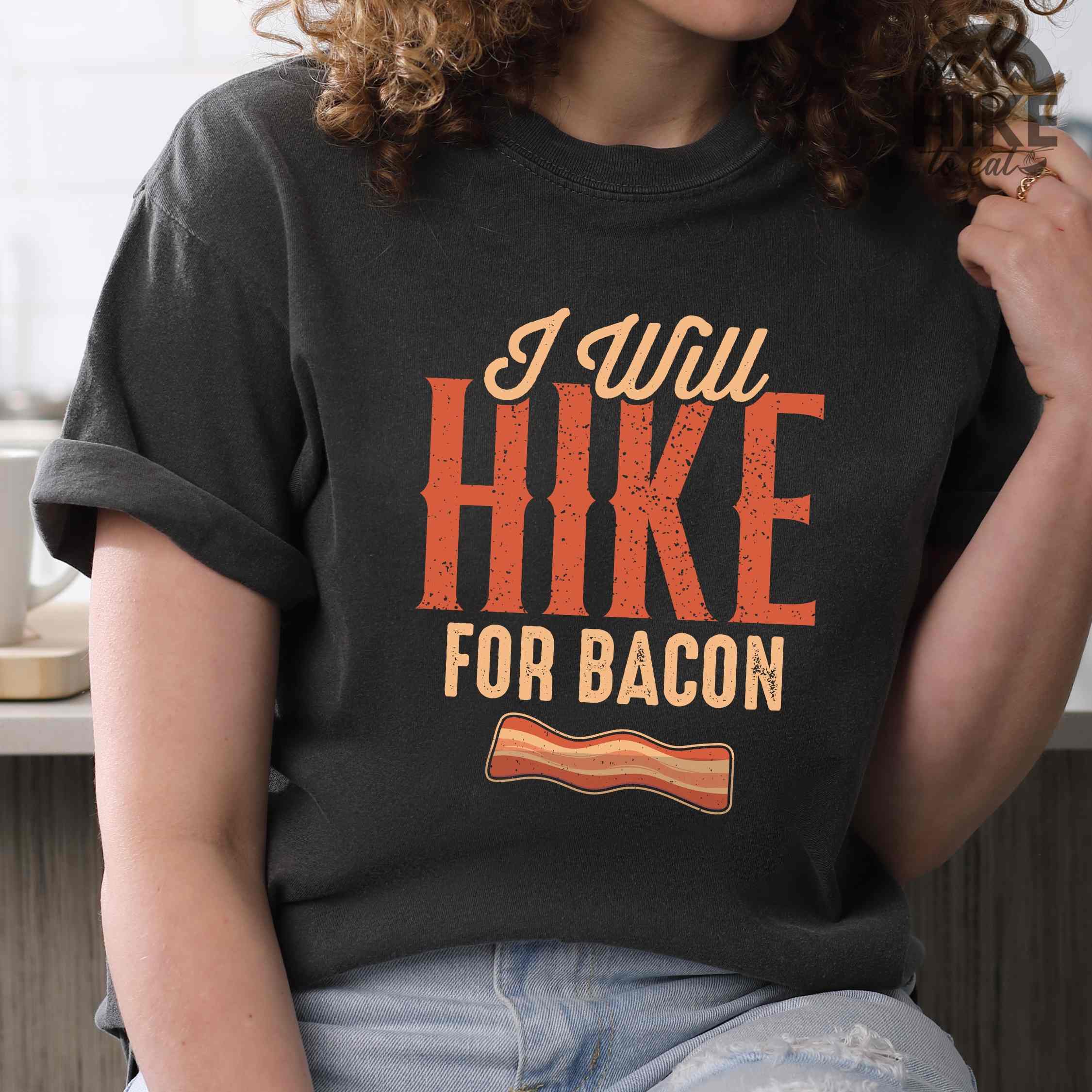 Woman wearing pepper "I Will Hike for Bacon" colored vintage tee with bold typography, illustrated crispy bacon, perfect for breakfast lovers