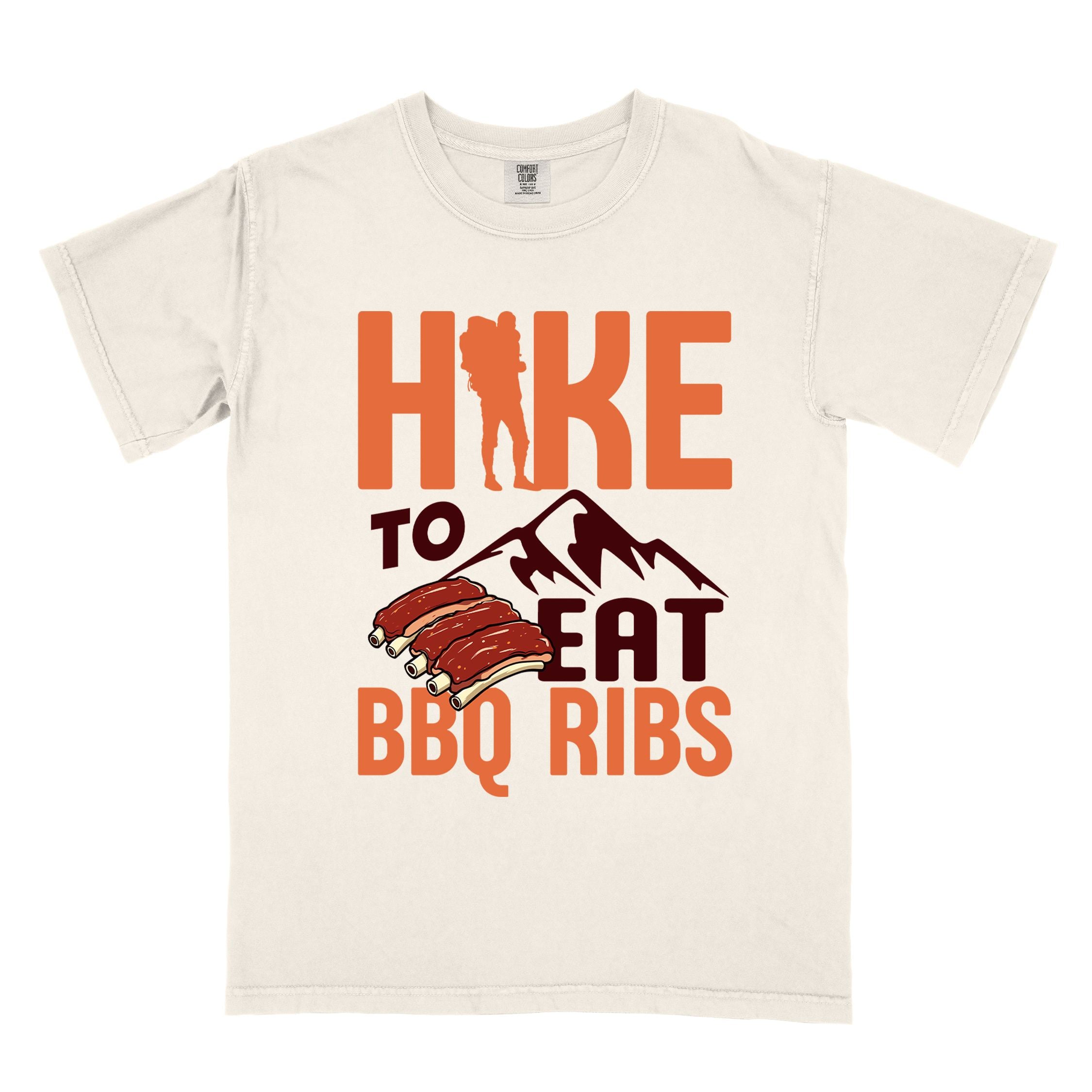 Ivory "Hike to eat BBQ ribs" colored vintage tee with bold typography, mountains, juicy grilled bbq ribs illustration, and backpacker for bbq enthusiasts