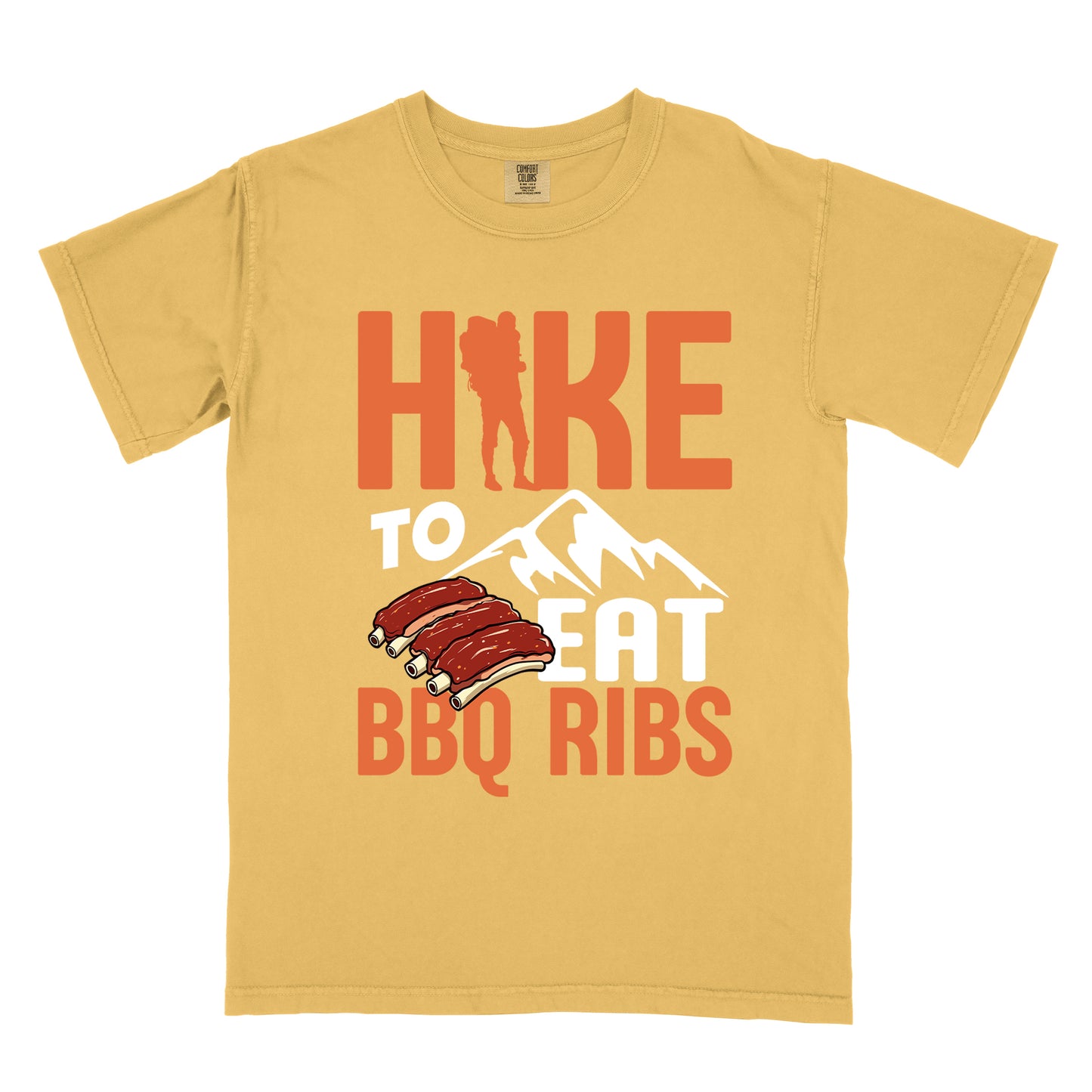 Mustard (Yellow) t-shirt with text "HIKE TO EAT BBQ RIBS". The word "HIKE" appears in orange with a hiker silhouette replacing the "I". Below that is "TO" in white text above a white mountain graphic. "EAT" appears in white, and "BBQ RIBS" in orange at the bottom. Between "EAT" and "BBQ RIBS" is an illustration of a rack of barbecue ribs with exposed bones.