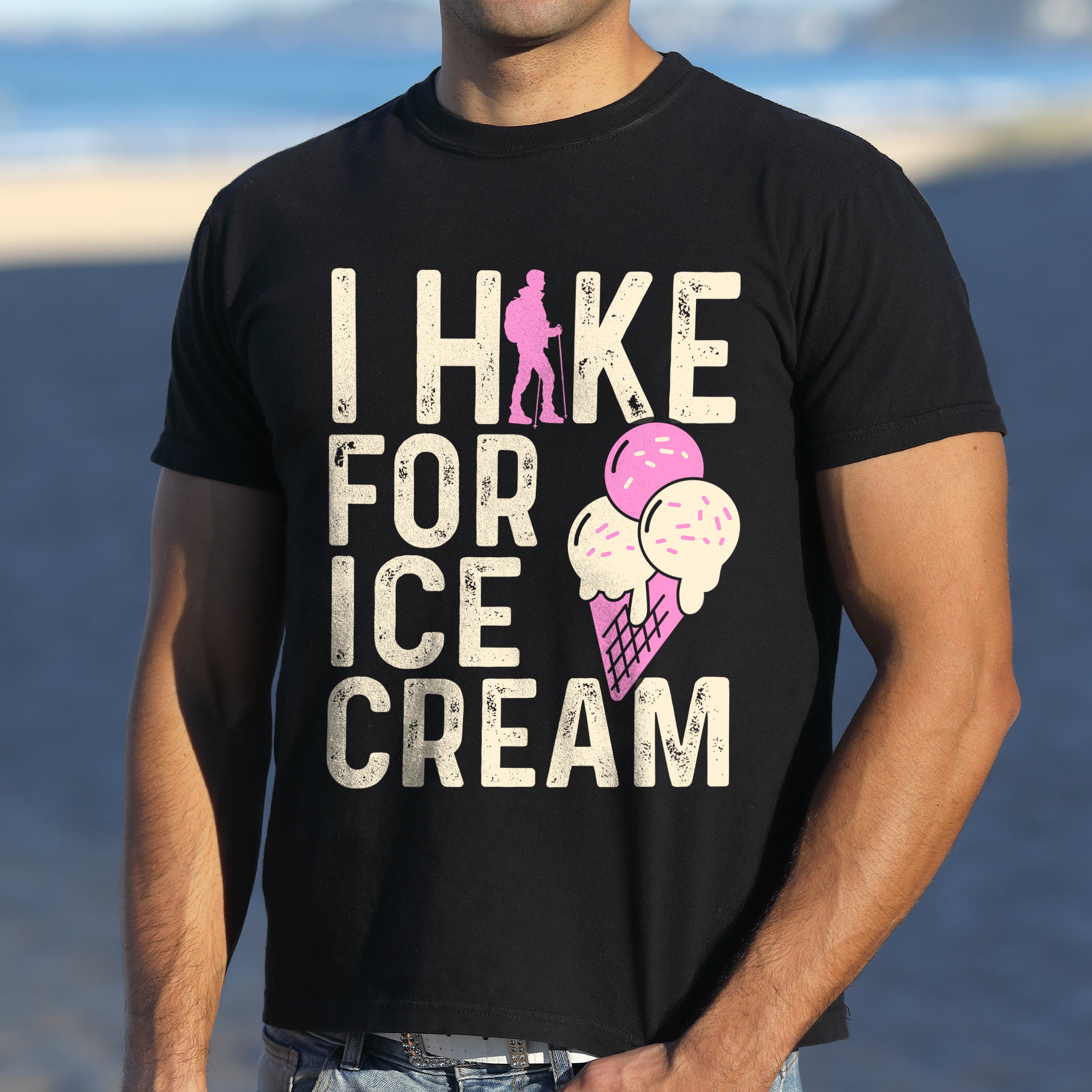 Black graphic t-shirt with 'I Hike for Ice Cream' text in cream lettering featuring pink hiker silhouette and colorful ice cream cone illustration with pink and cream scoops in purple waffle cone