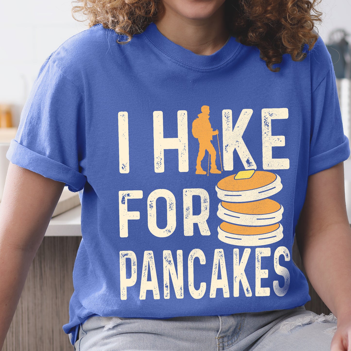 Flo Blue (Bright Blue) graphic t-shirt with 'I Hike for Pancakes' text in cream lettering featuring orange hiker silhouette and stack of golden pancakes illustration
