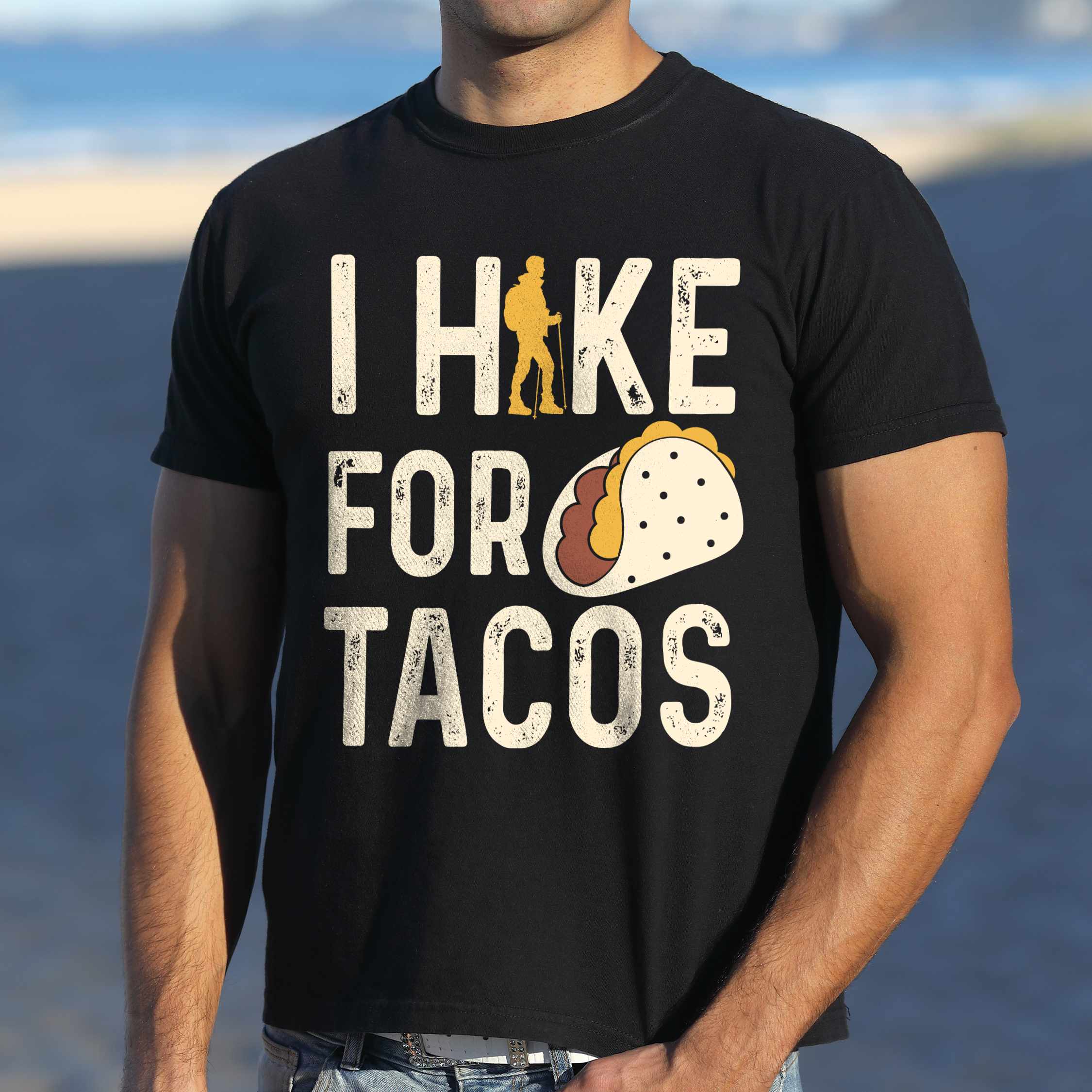 Man wearing black colored vintage tee with 'I Hike for Tacos' text in cream lettering, illustrated taco, and backpacker for taco lovers