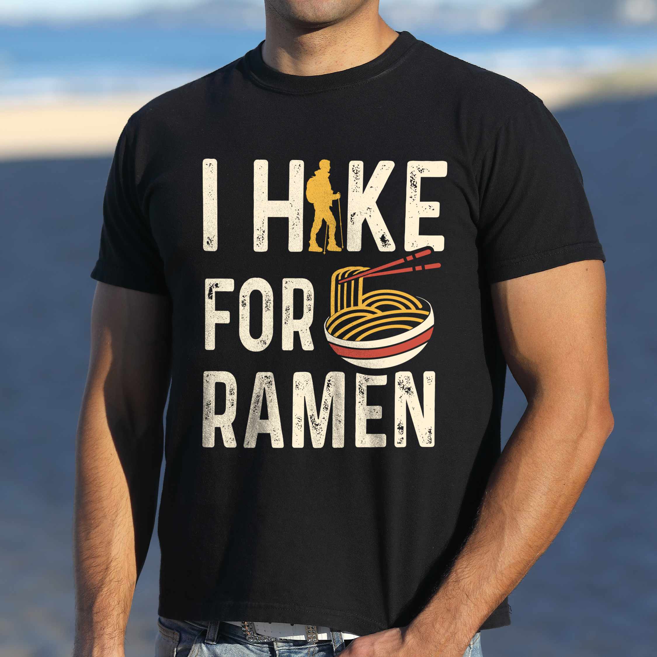 Man wearing black colored vintage tee with 'I Hike for Ramen' text in cream lettering, illustrated taco, and backpacker for ramen lovers
